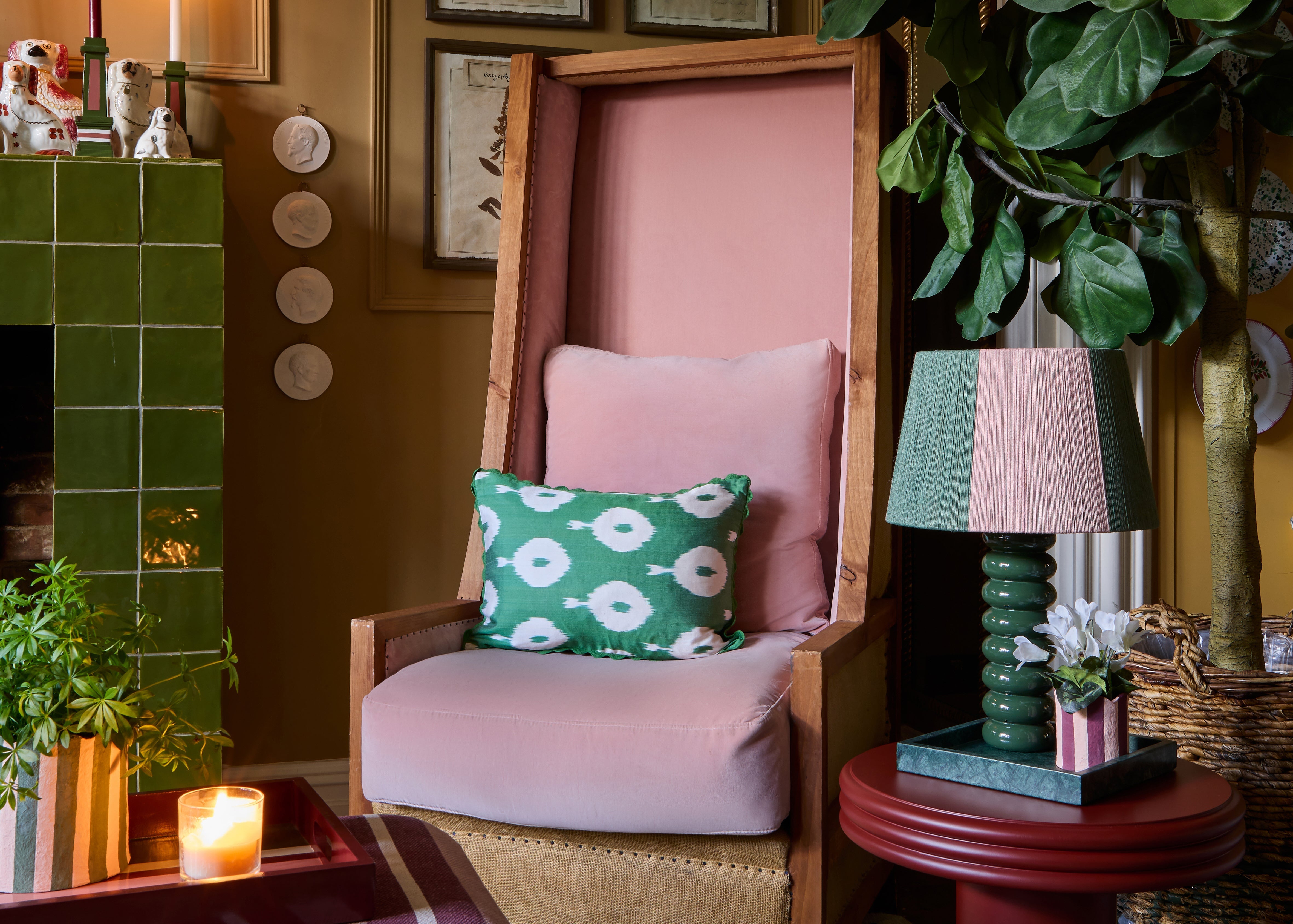 Green and pink striped lampshade, on the red table family, next to a pink chair with a green ikat cushion