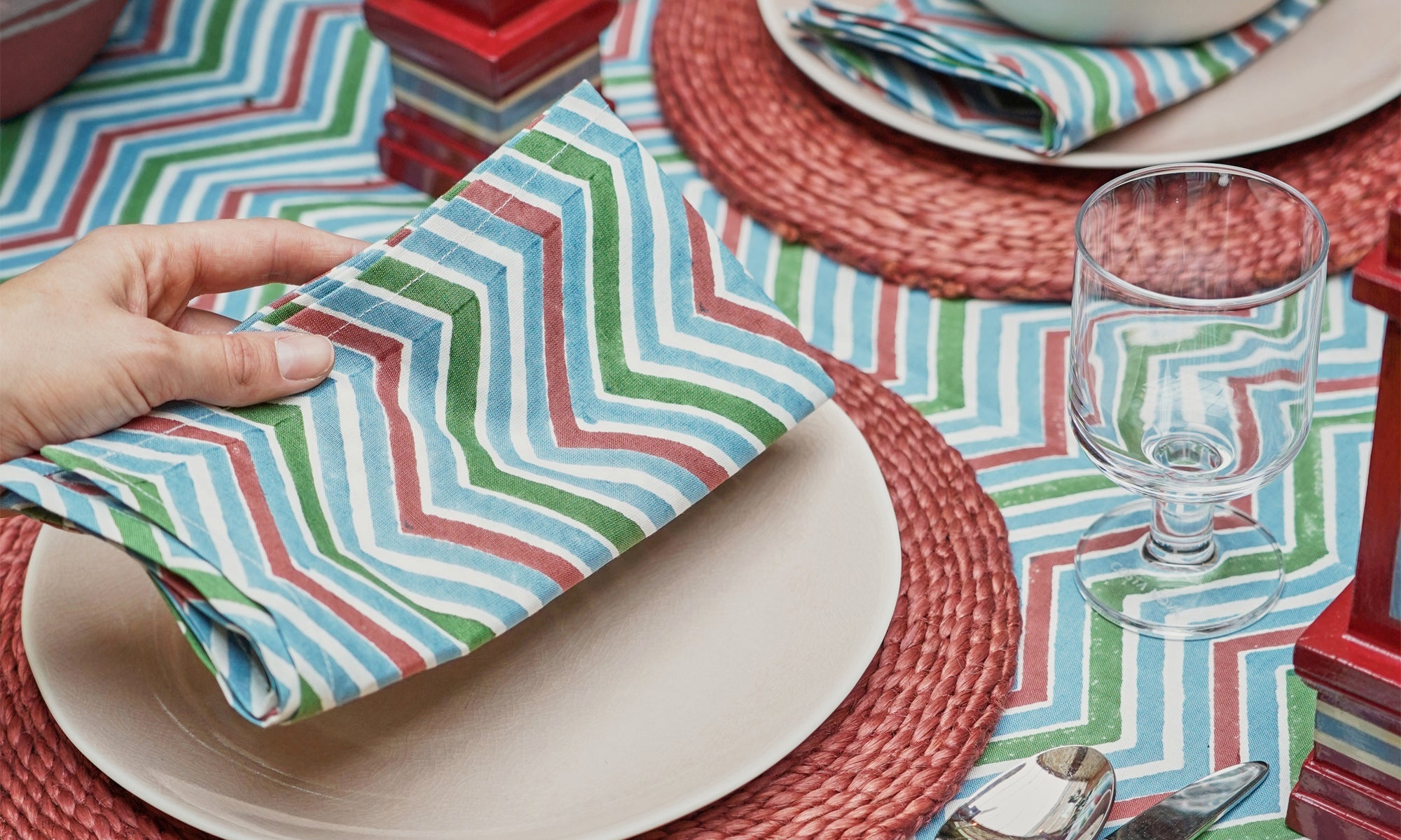 Chevron block printed napkin being placed on a blue and red tablscape