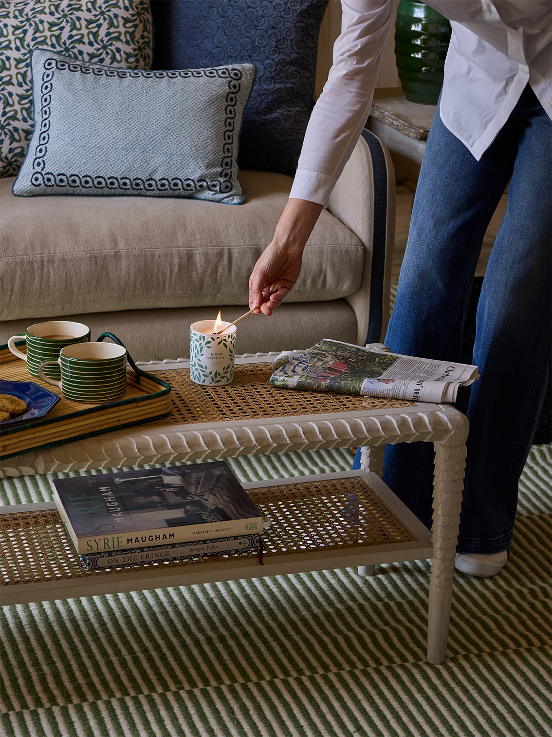 Person lighting a candle on a coffee table