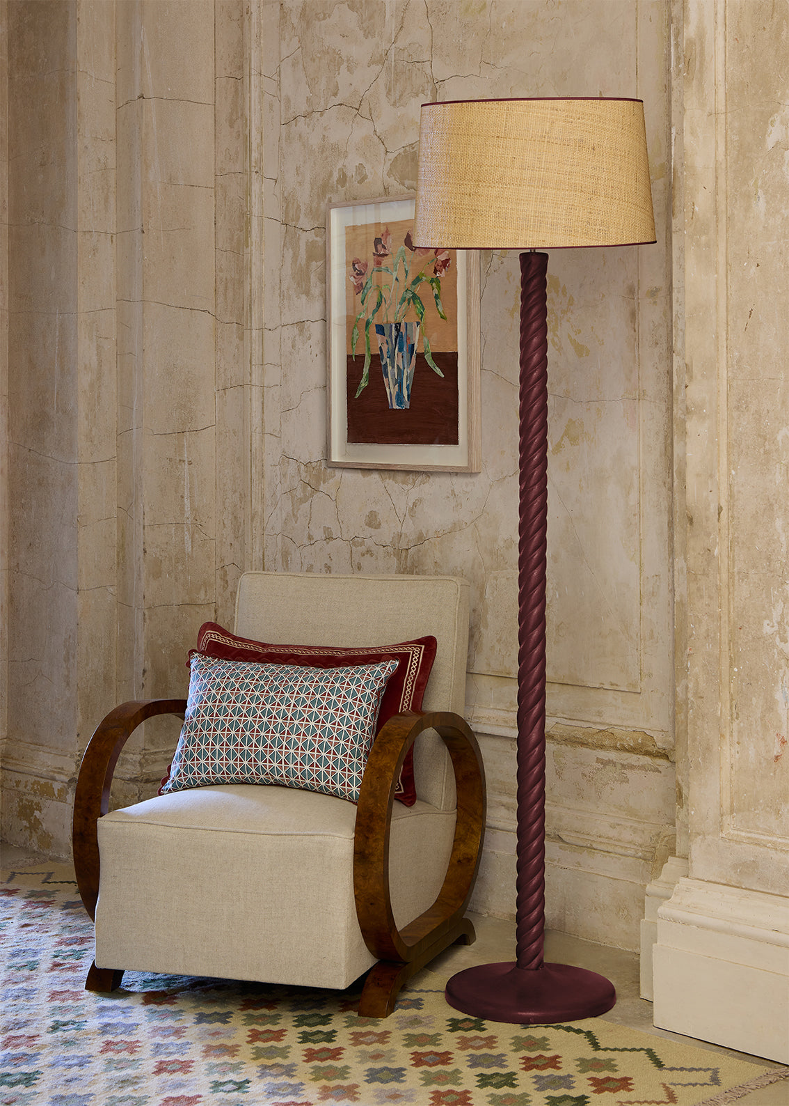 Red floor lamp next to armchair with red and blue cushions