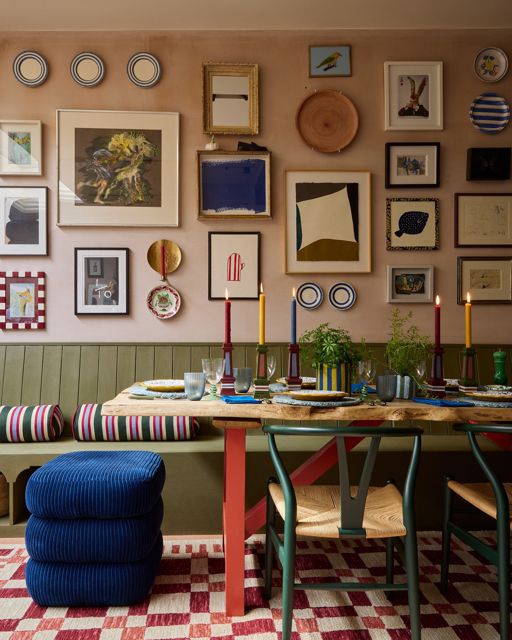 A colourful dining room is set up for dinner, the table display features the grown up candlestick, glassware, jute placemats and plants in the must have planter. Under the table are the classic stool and check mate rug in red.