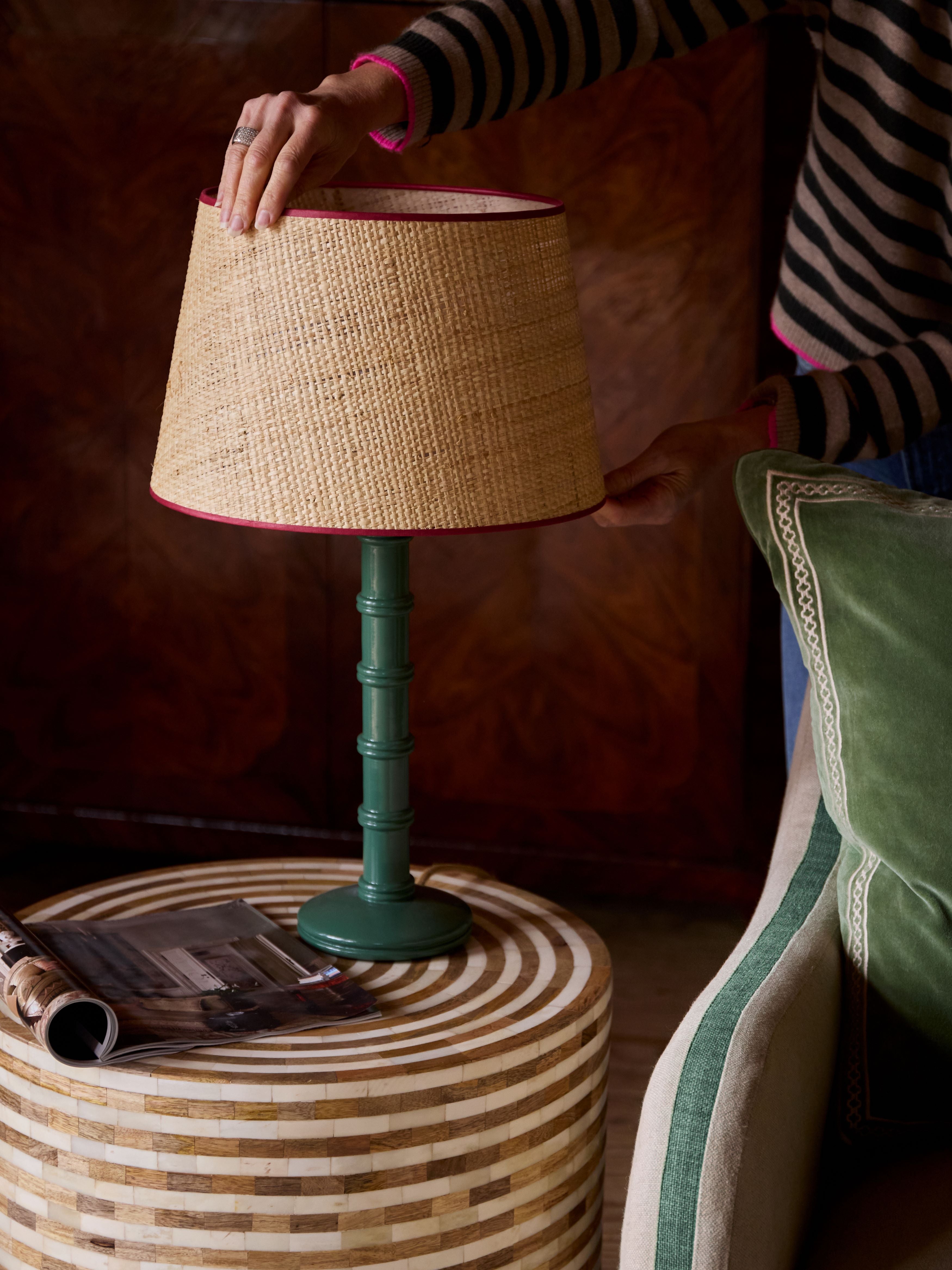 a model arranges a seema lampshade on a green column lamp