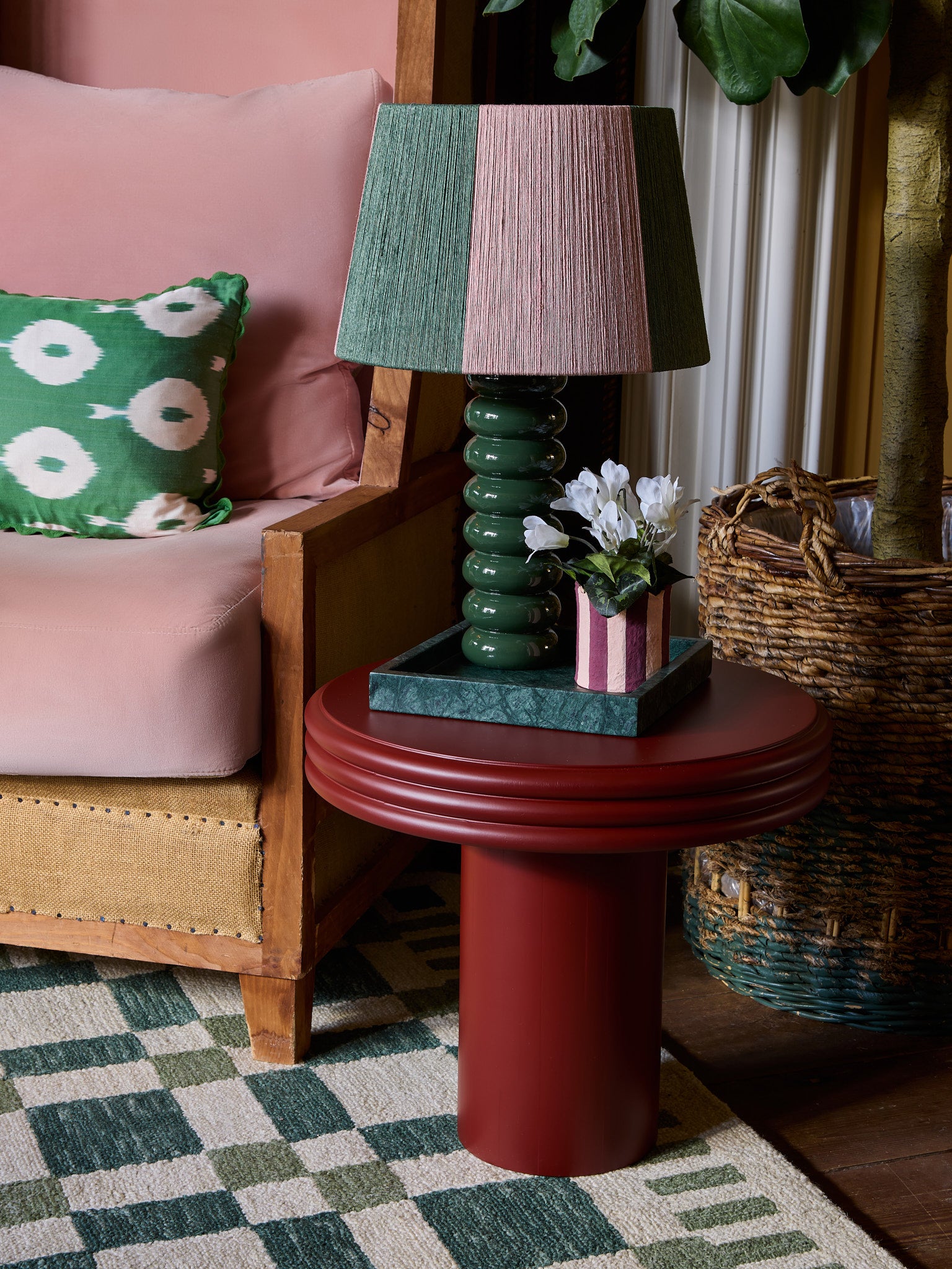 The goes anywhere table lamp is on a small red table with the pen house planter in pink and red, the check mate rug in green is underneath