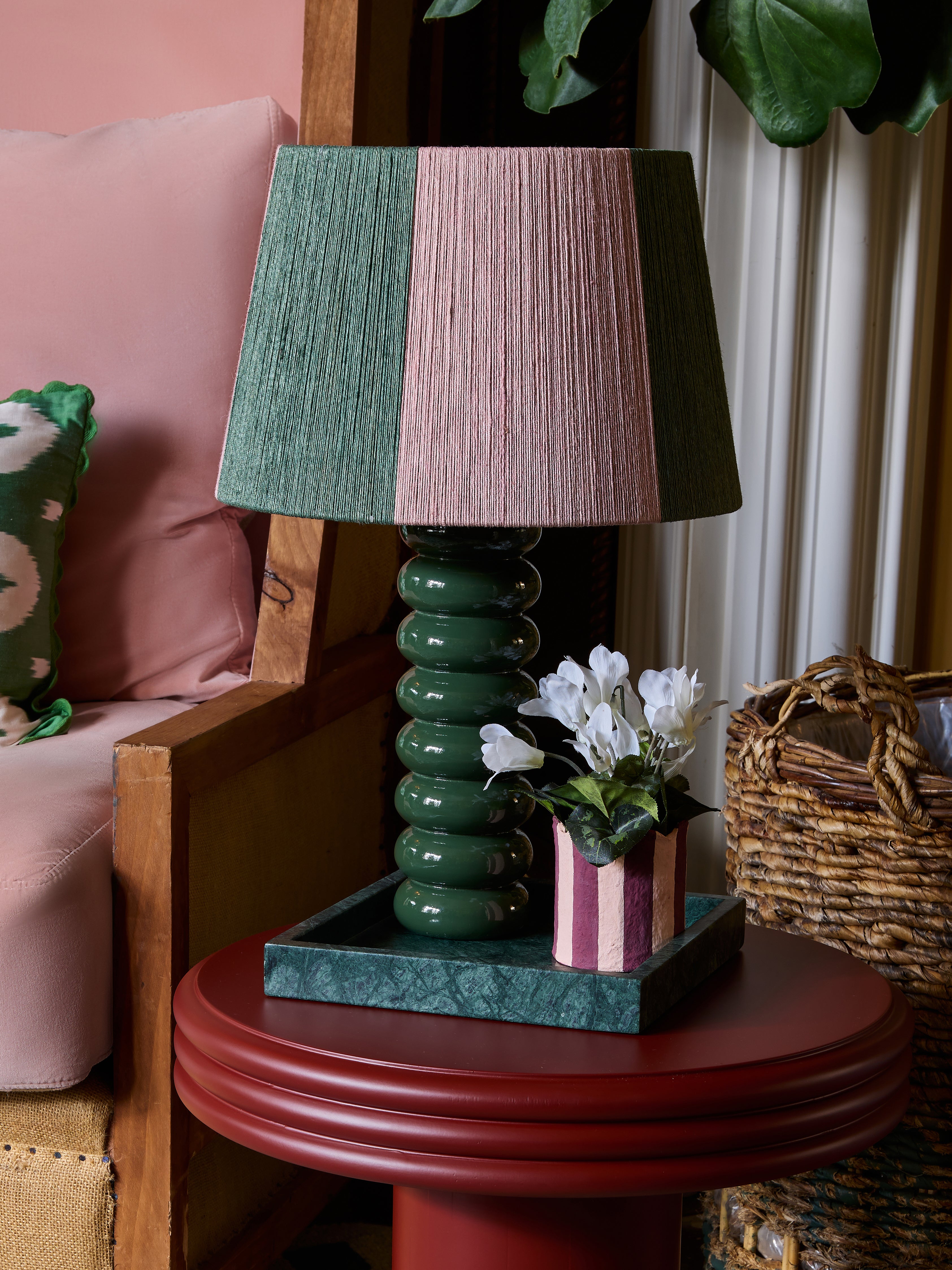 The goes anywhere table lamp on a red table with the stripey string lampshade and the pen house