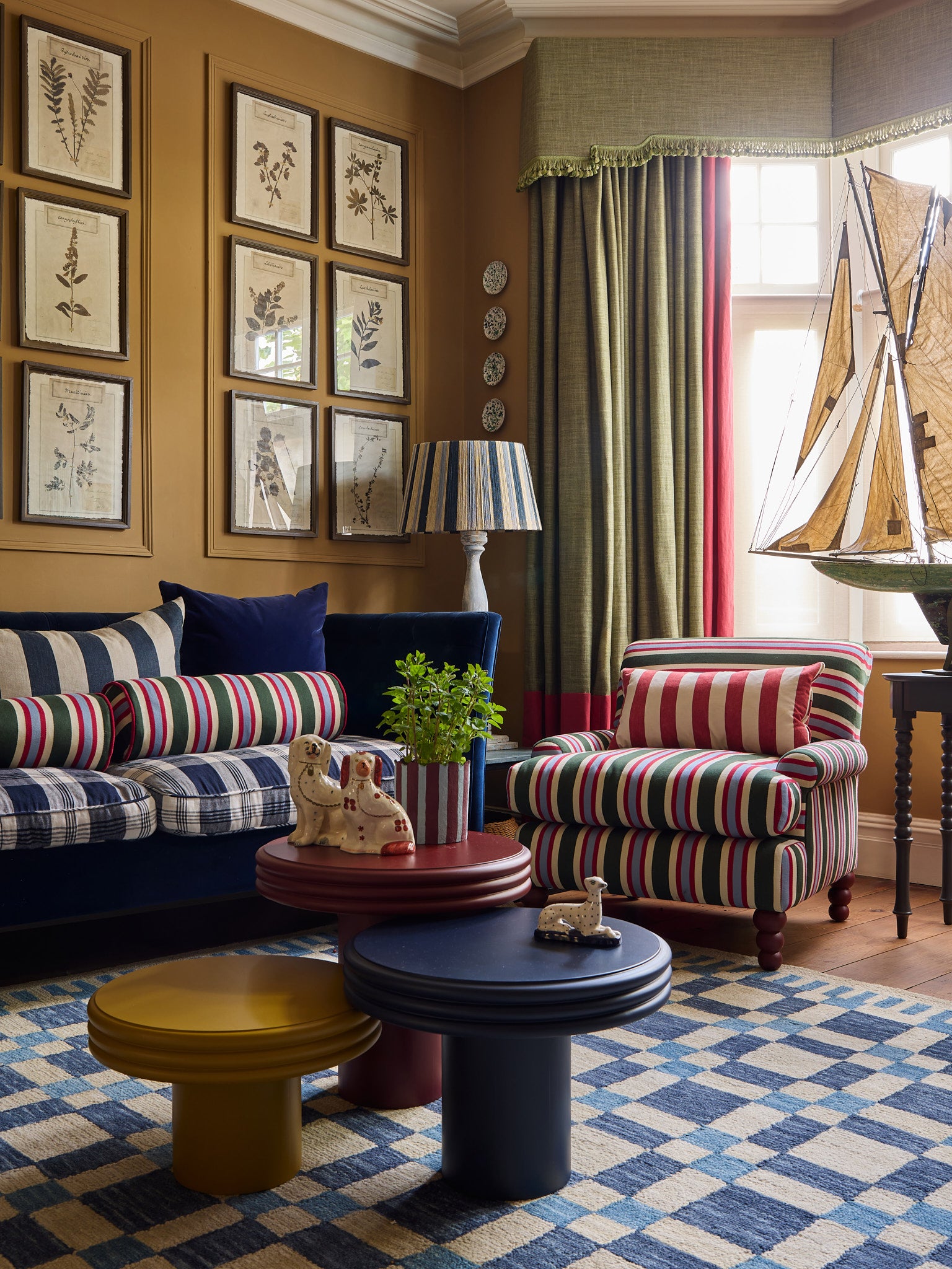 The table family sit on a check mate rug in front of a blue sofa and the striped heaven chair