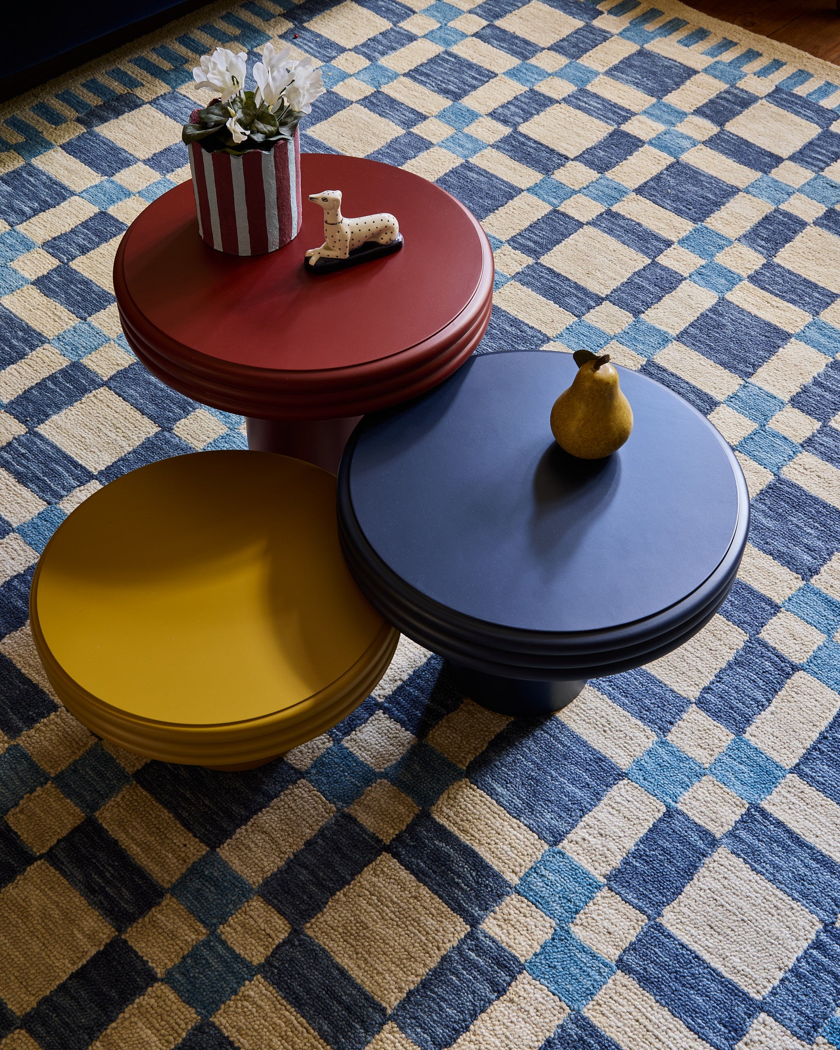 The table family features 3 tables in red, yellow and blue, this set is styled with the check mate rug in blue and a must have planter.