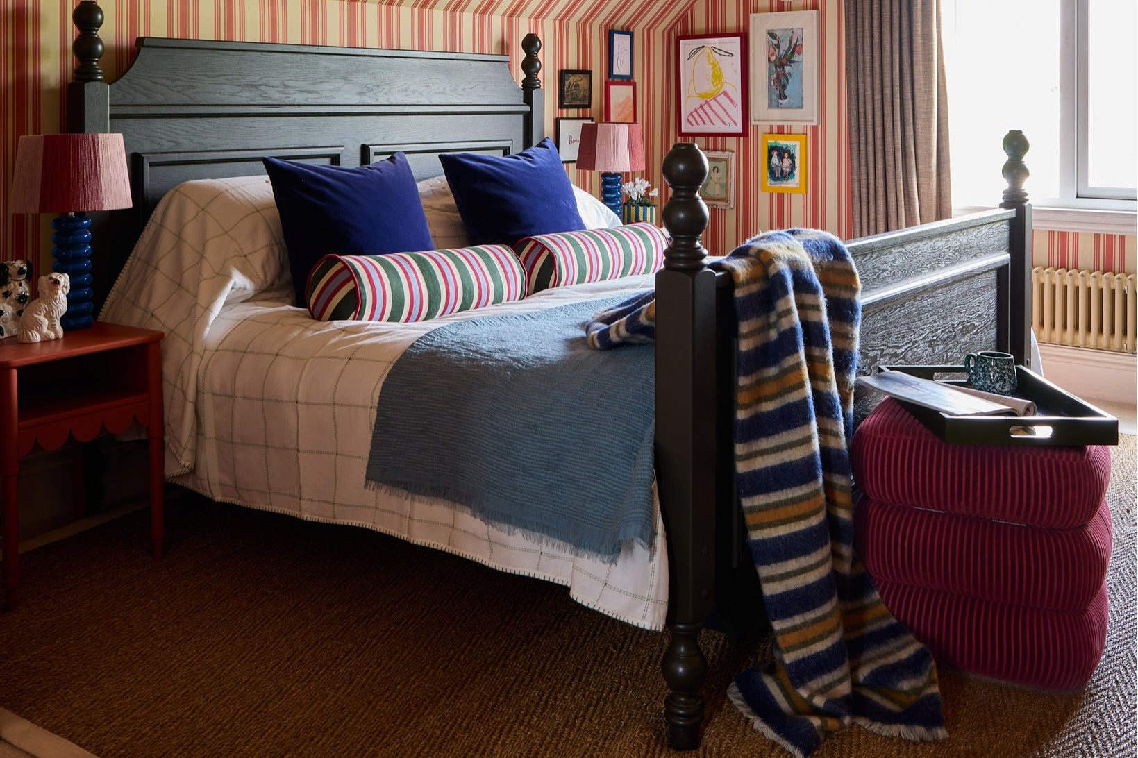 Sarah's bedroom with striped bolster cushions on the bed and a striped throw draped over the end of a bed next to the red classic stool