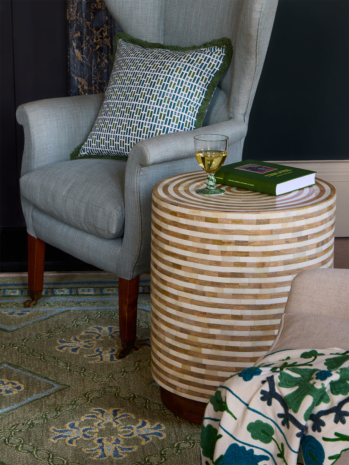 Armchair with green and blue cushion next to a side table