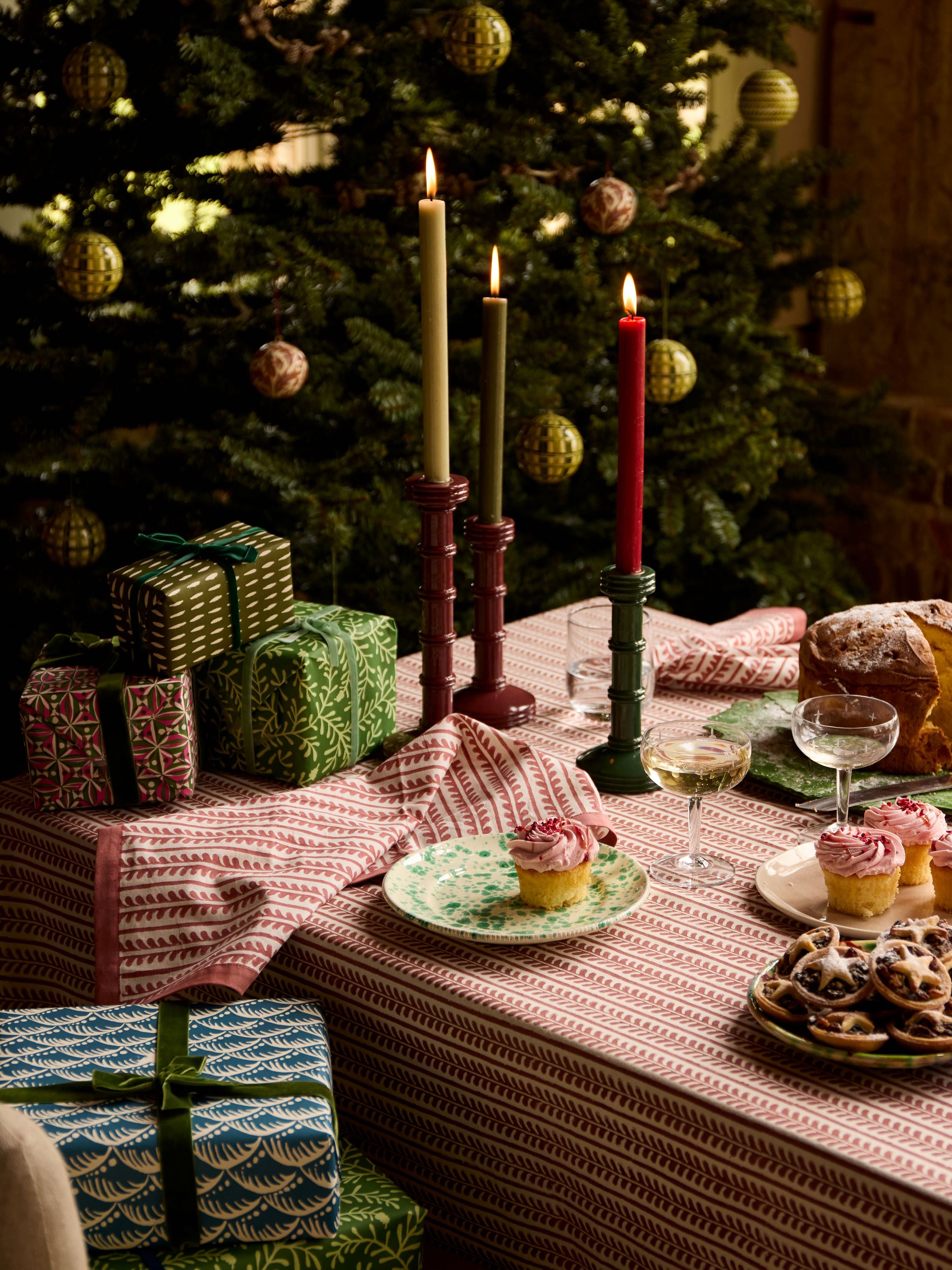 A portrait shot of a festive tablescape by Birdie Fortescue featuring bel table linen, twisted candlesticks and sweet festive treats