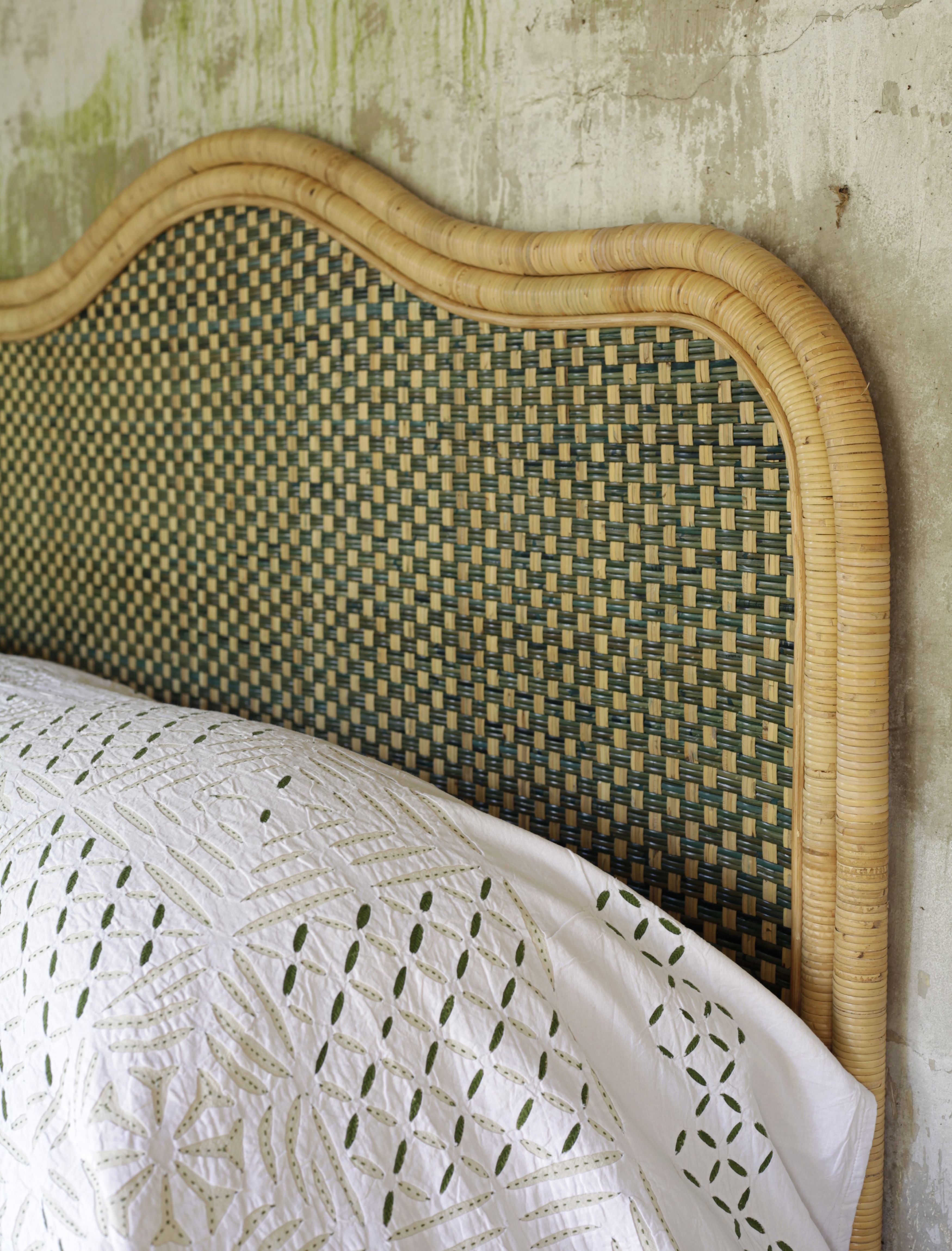 the rattan headboard against a wall with an applique white bedspread