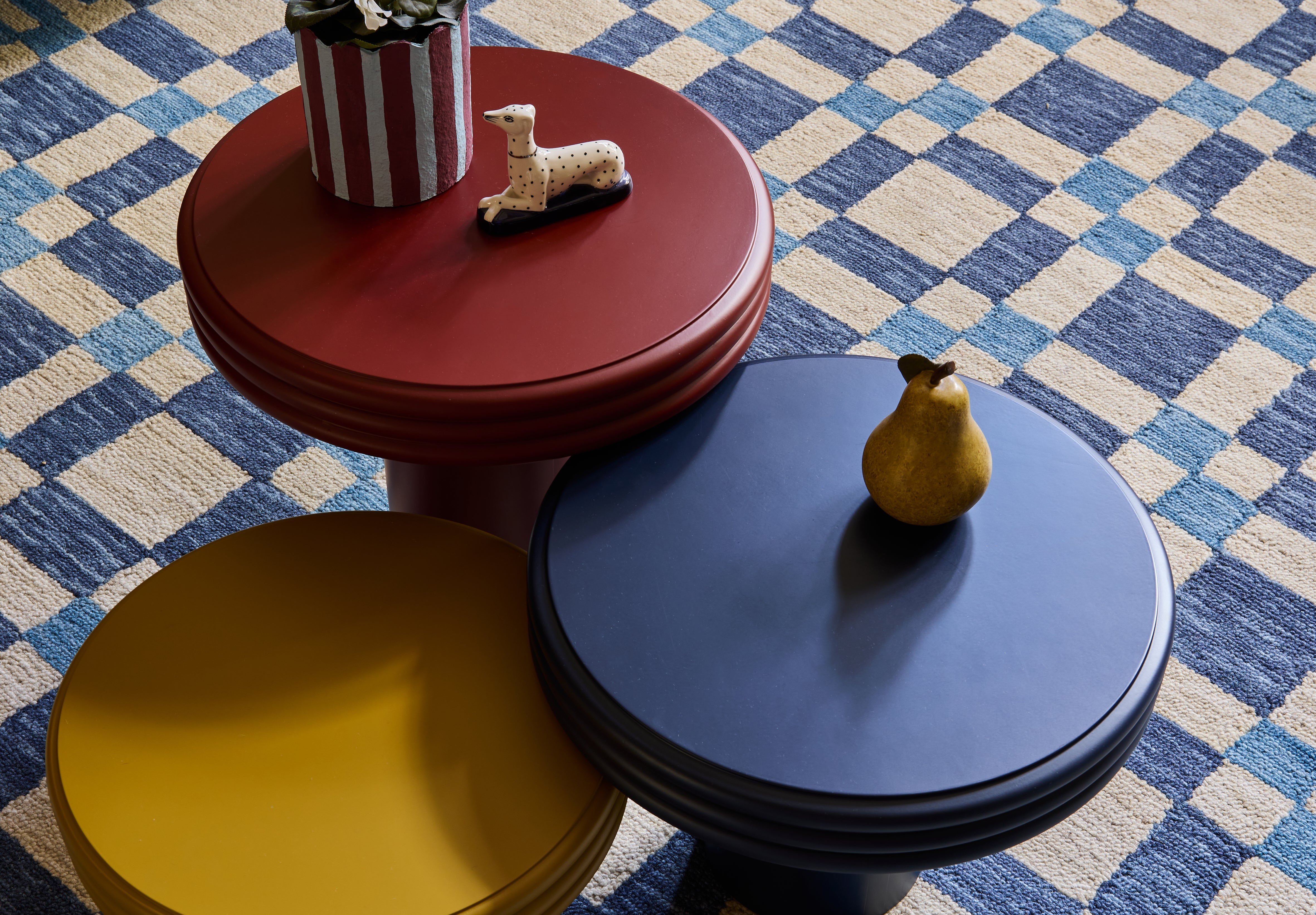 three small tables are arrangement on a blue and white check rug