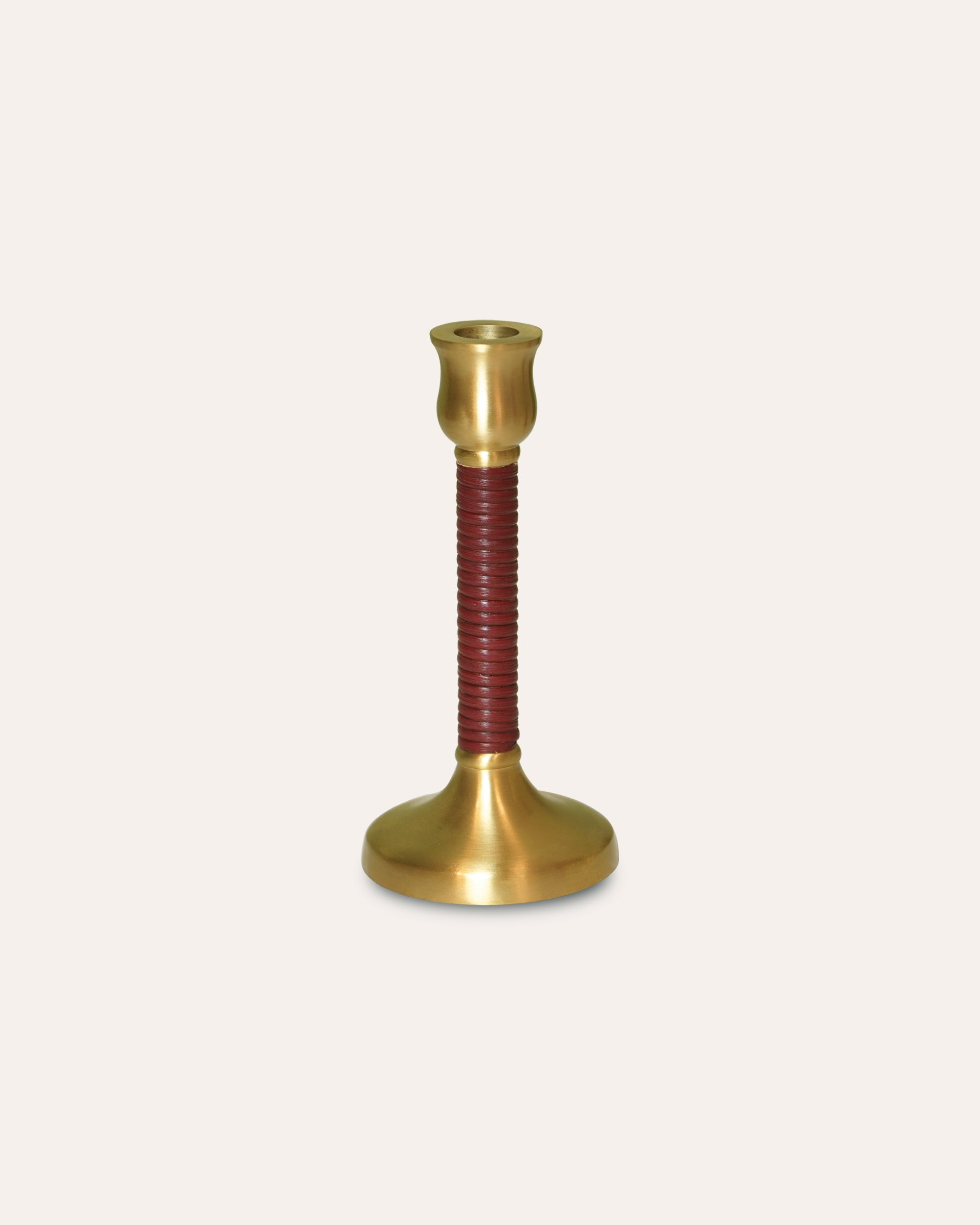 Brass candle holder with a red ribbed base on a beige background