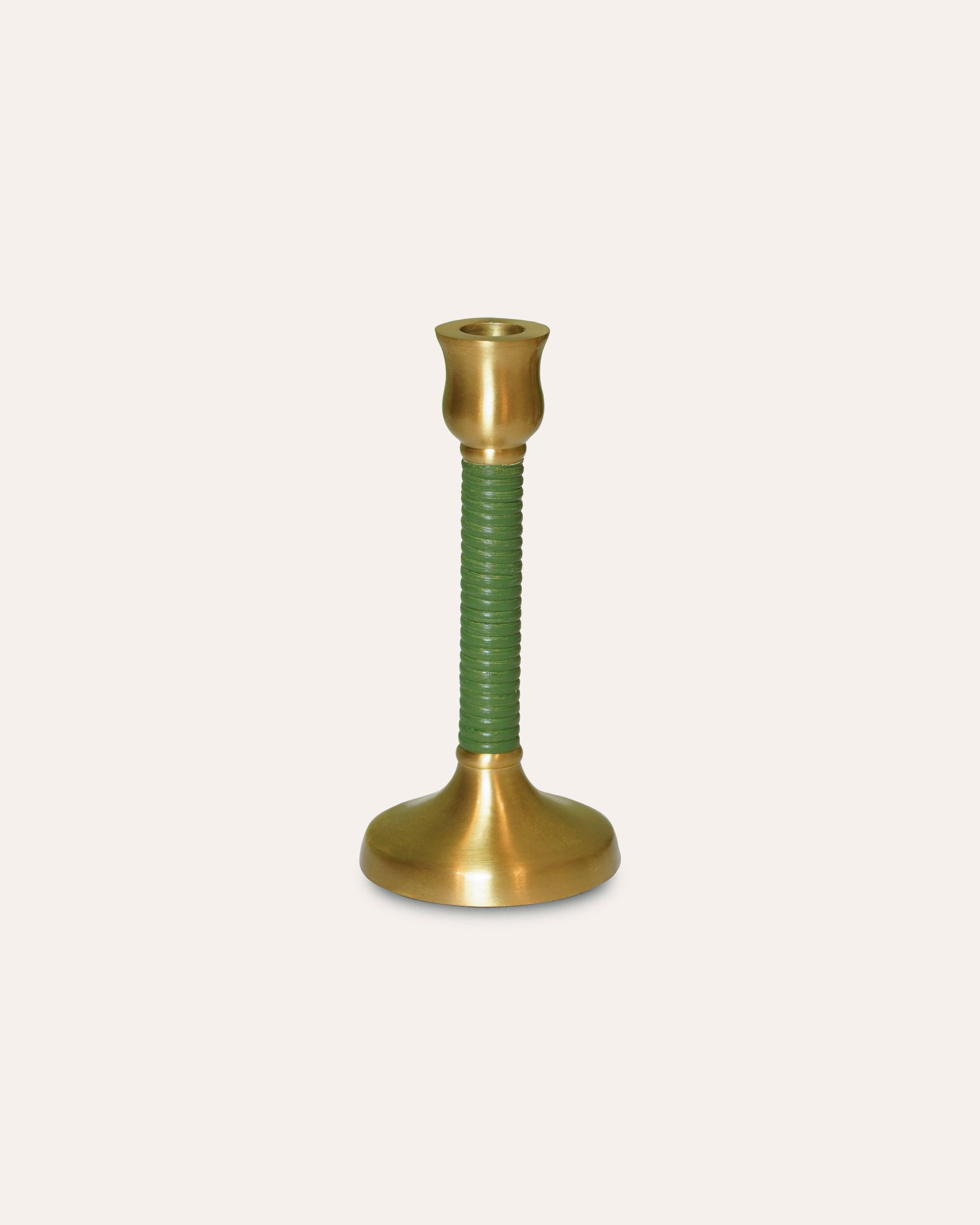 Brass and green candle holder on a beige 
background