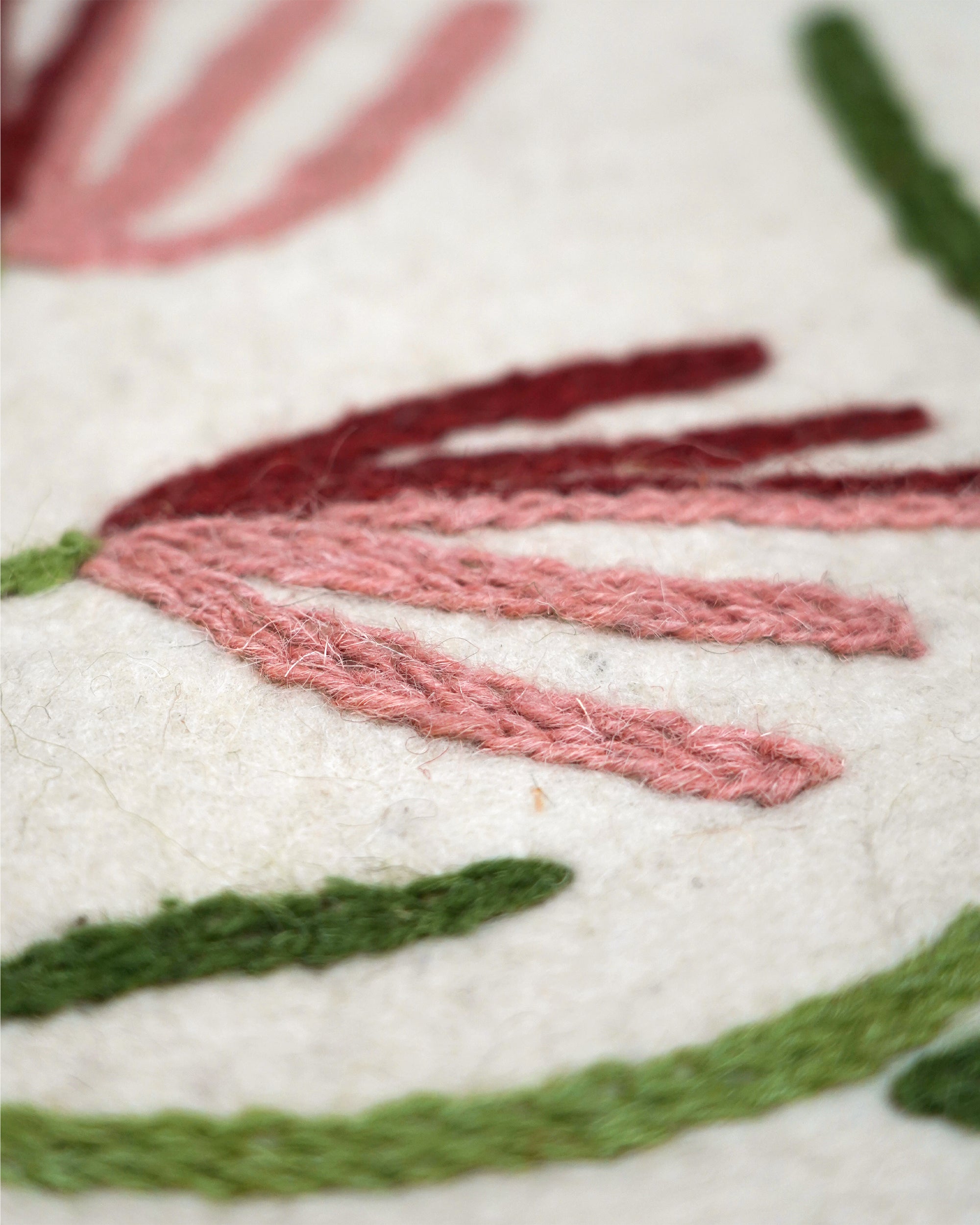 Close-up of embroidered fabric with pink and green thread