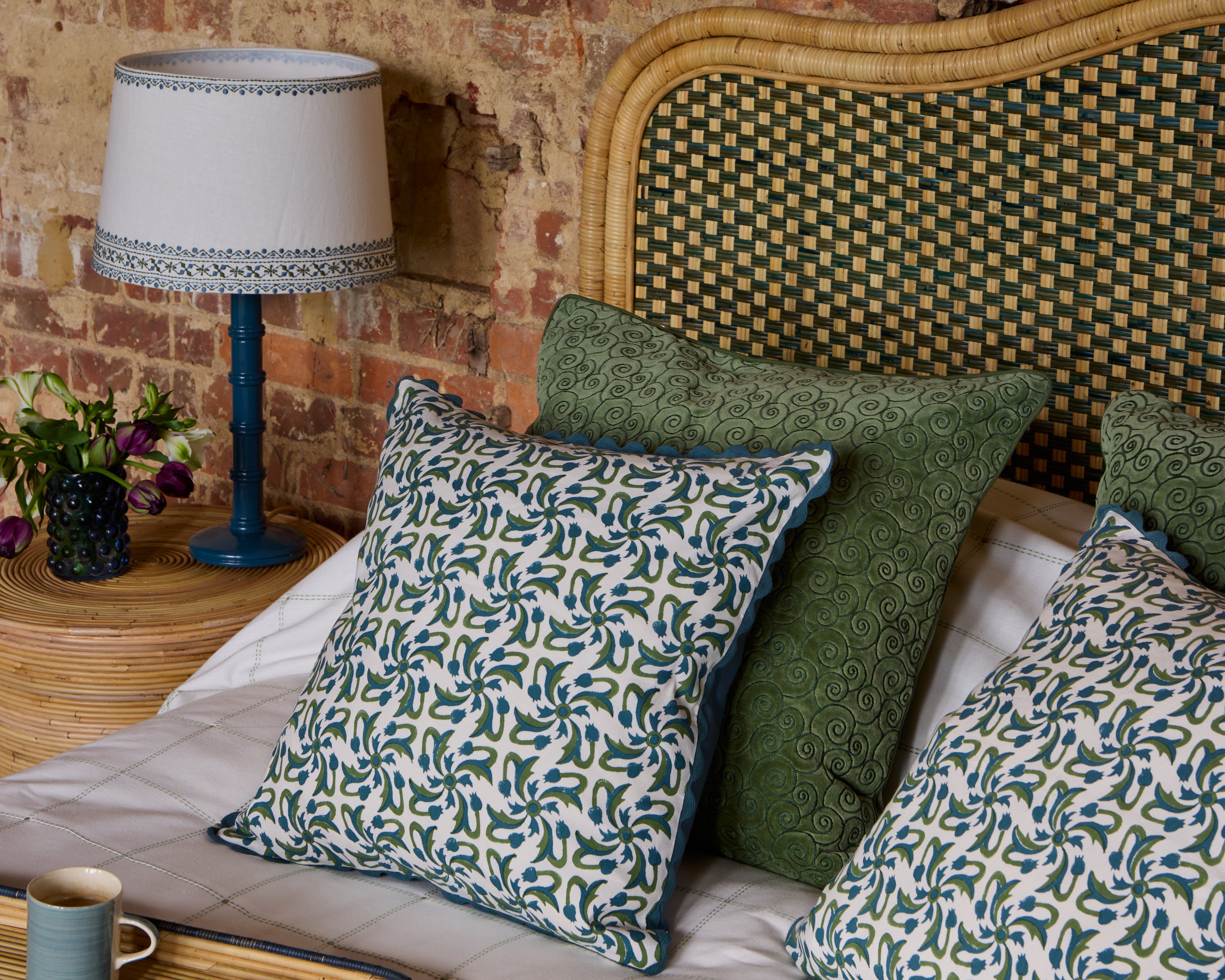 Green and blue bedroom lifestyle image, showing our Rueda Tile Print cushion and green Remolino cushion