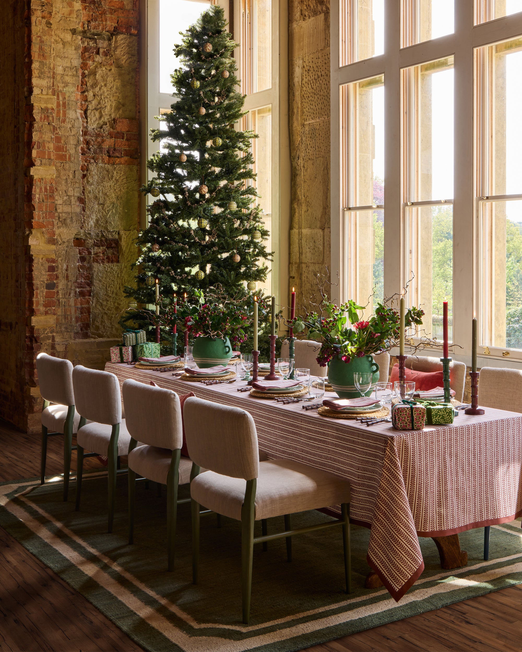 Red and green festive dining table, with red bel table linens, red and green column candlesticks, and green cotton mache vase