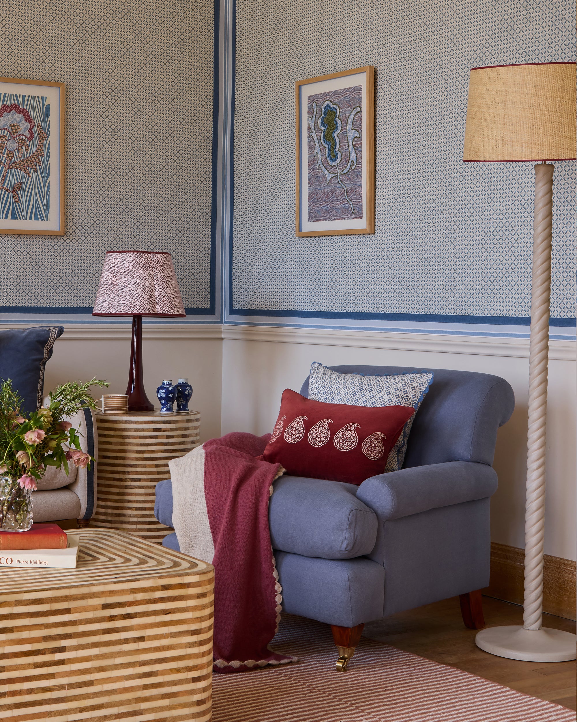 Living room with a blue armchair, red blanket, and decorative pillows.