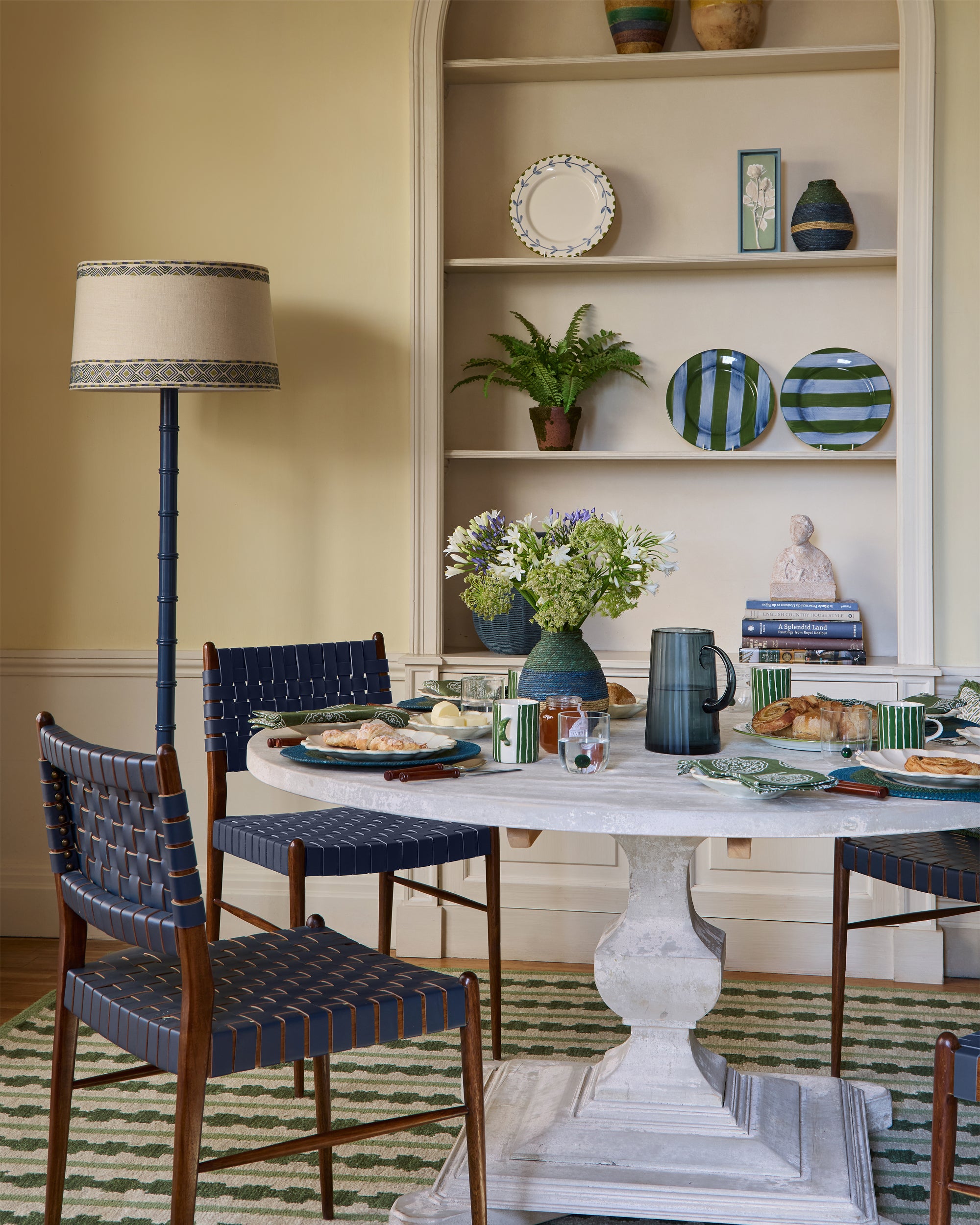 Dining room with a table set for a meal, chairs, and decorative elements.