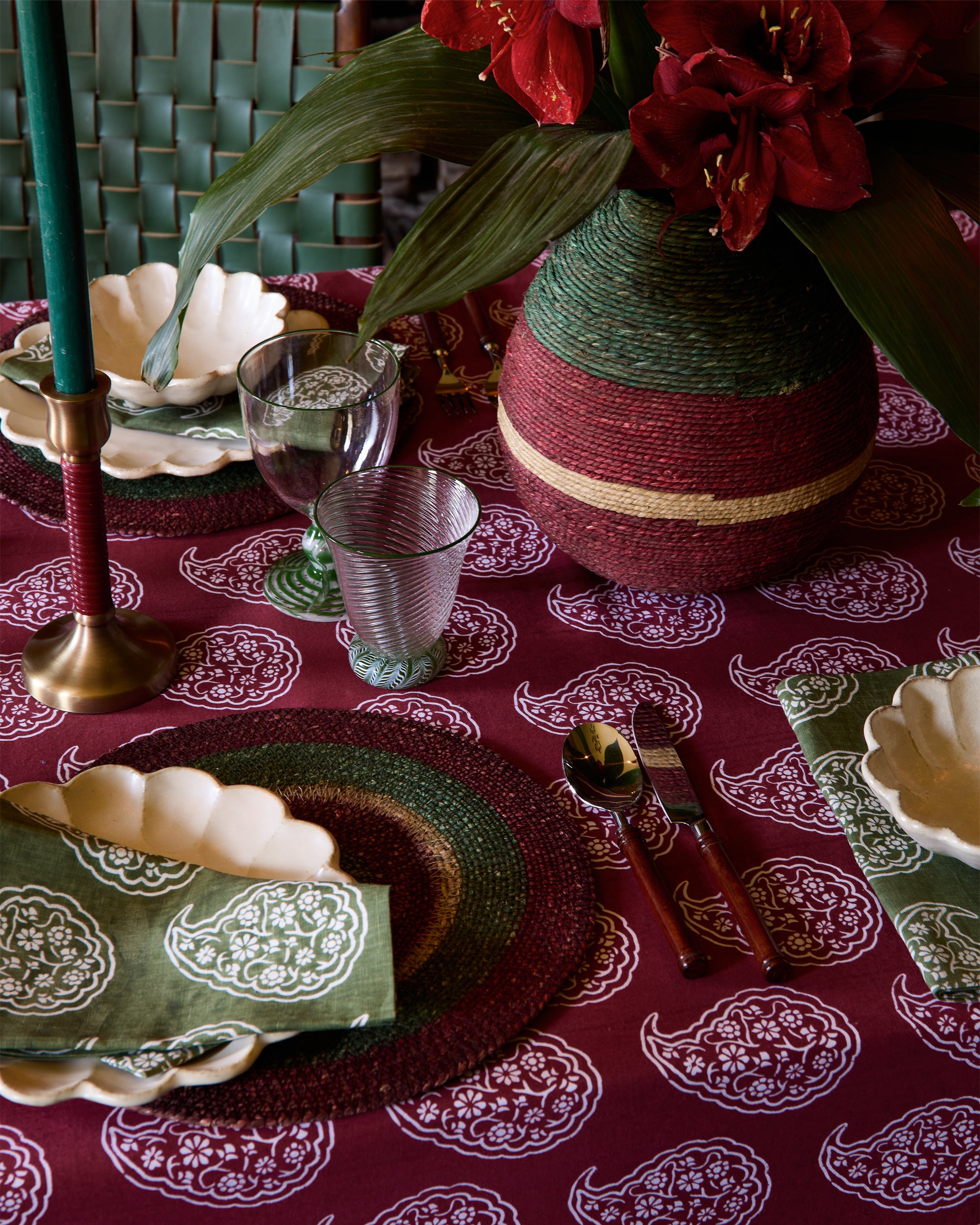 Decorative table setting with red and green elements on a patterned tablecloth.