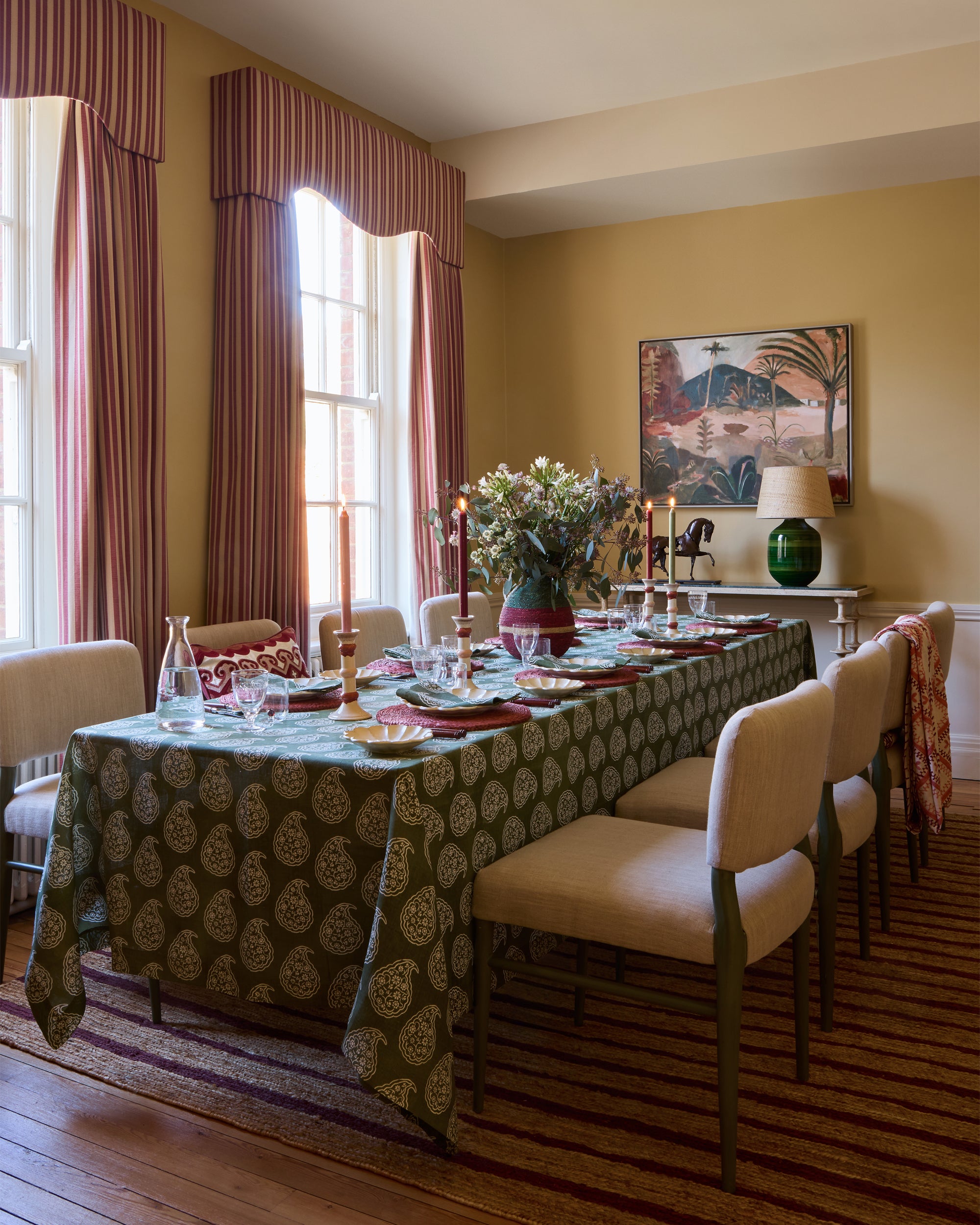 Dining room with a patterned tablecloth, chairs, and a large window.