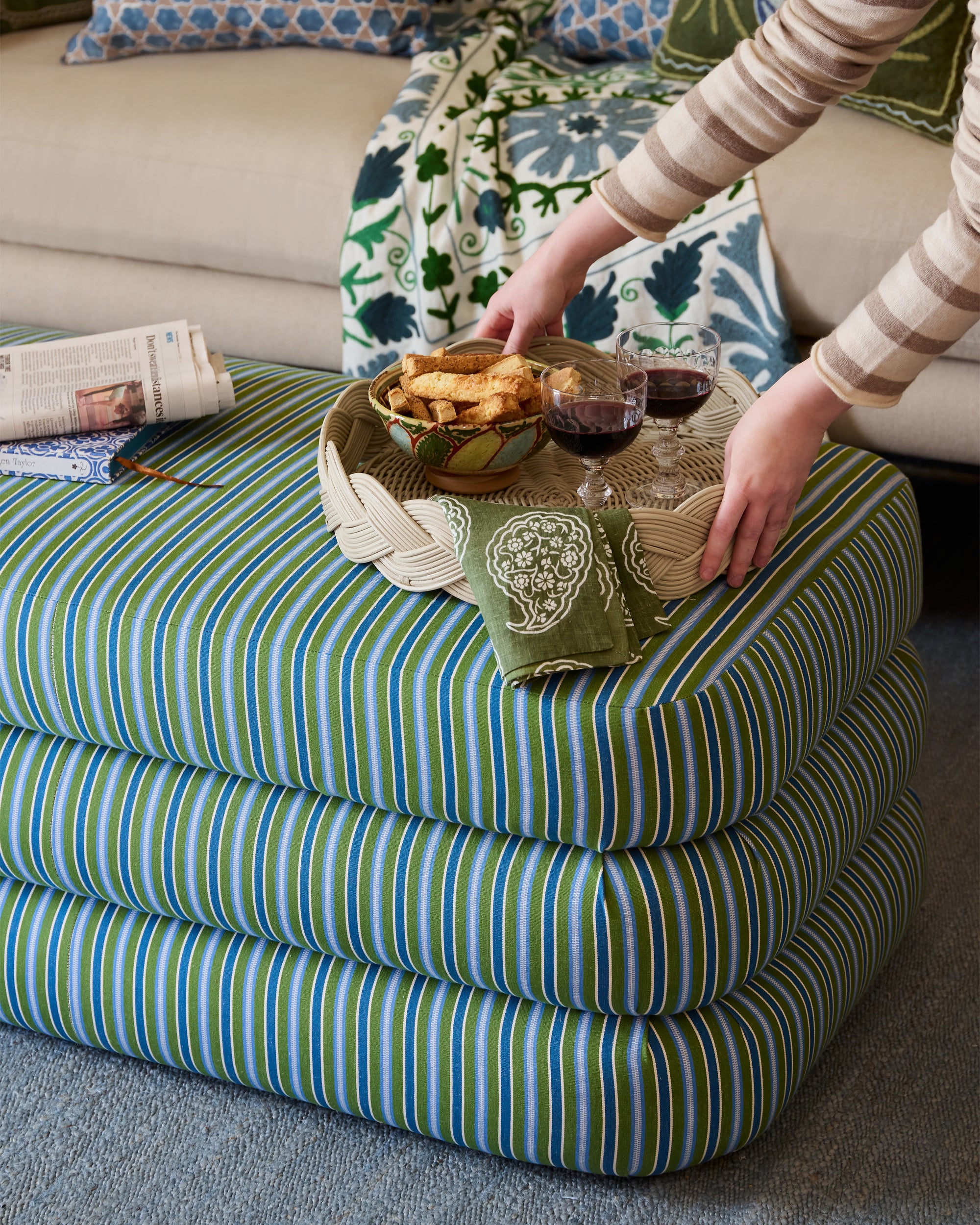 Person placing decorative tray on top of the striped ottoman