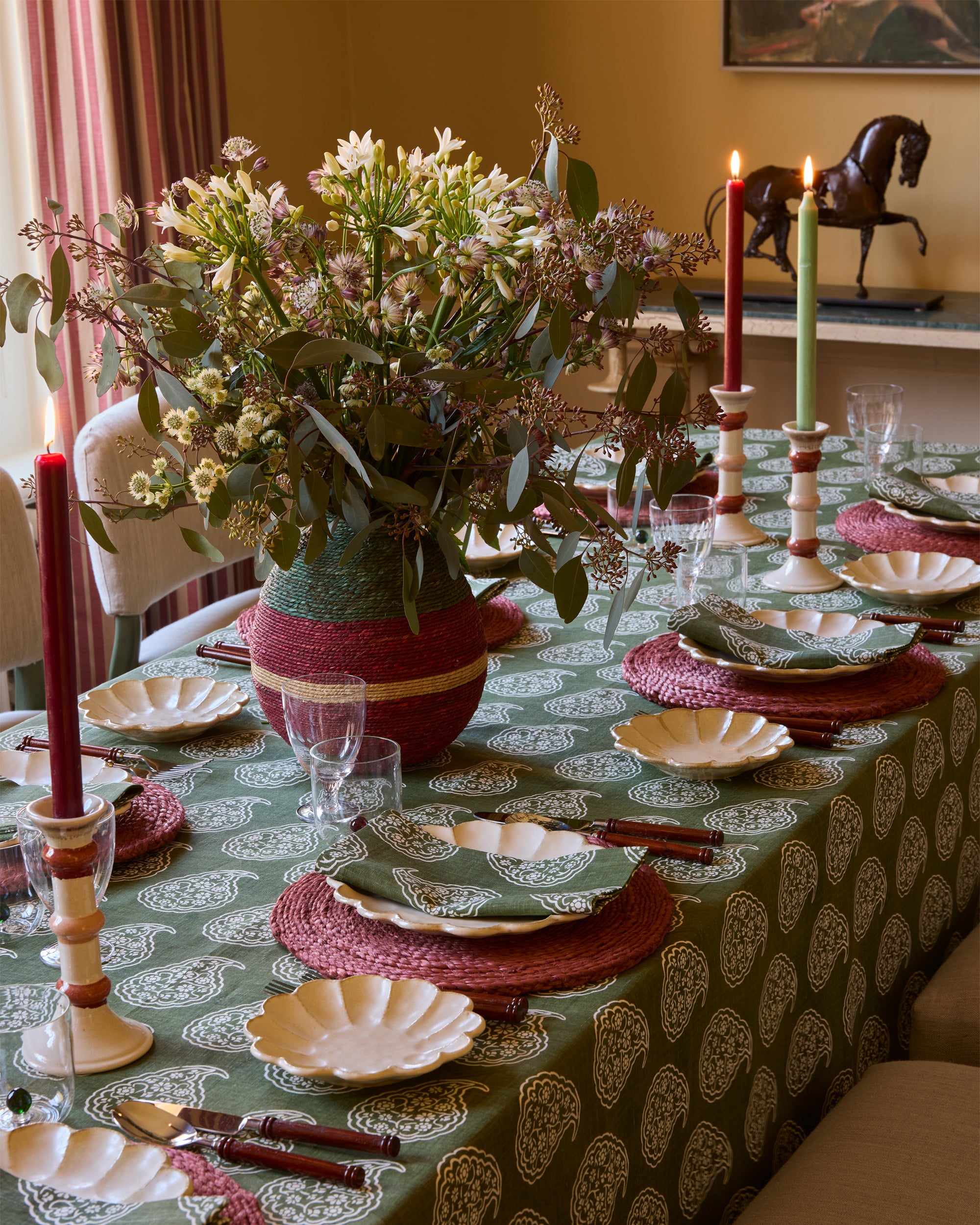 Decorative table setting with flowers, candles, and patterned tablecloth.
