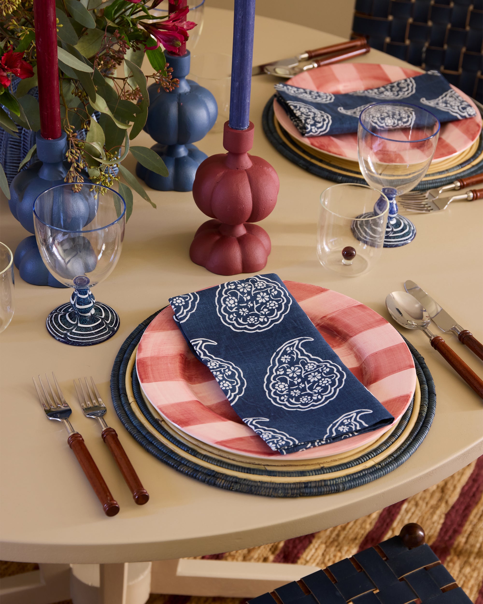 Decorative table setting with pink and blue patterned napkins, plates, and glasses.