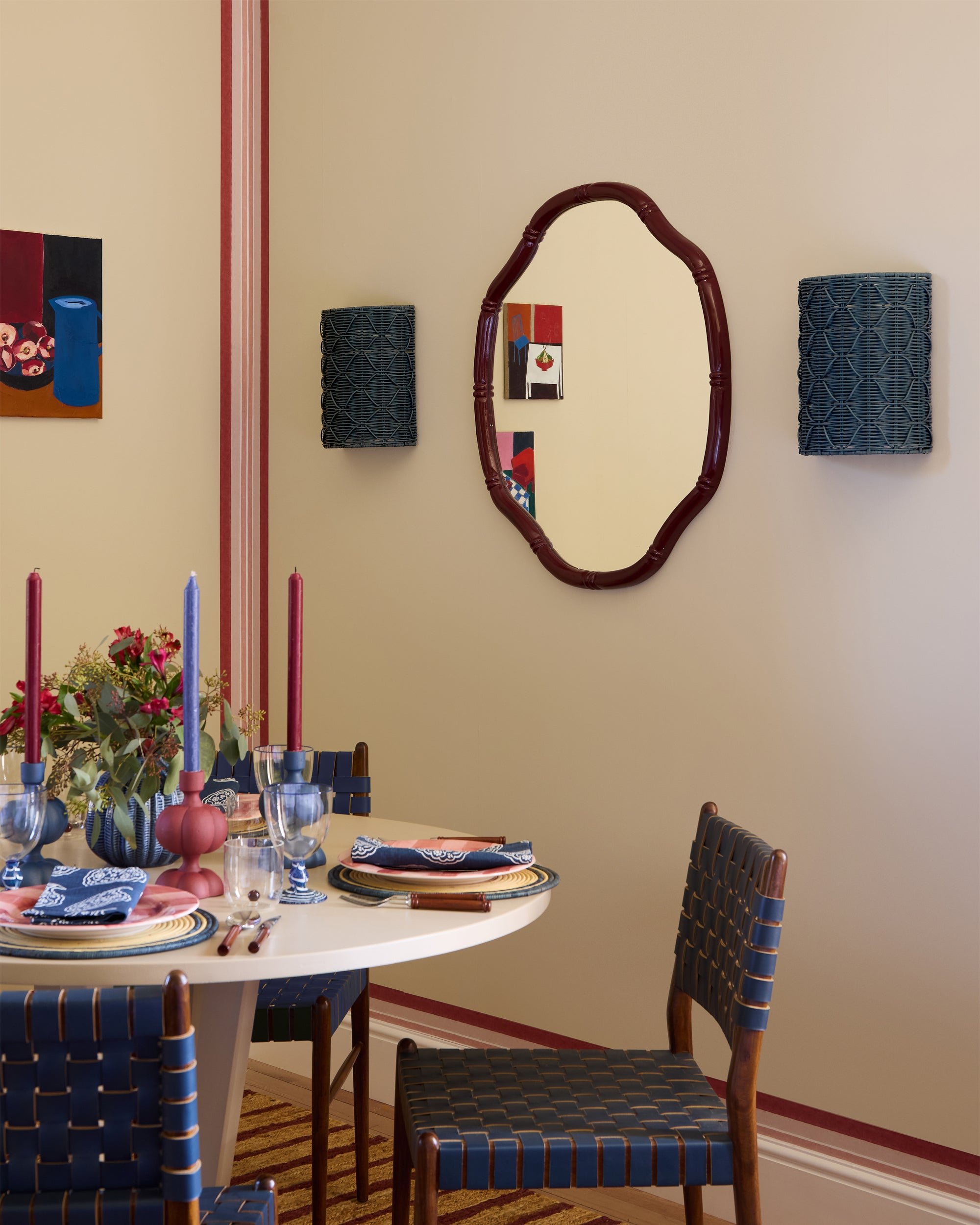 Dining room with a round table set for four, chairs with blue and red patterns, and a mirror on the wall.