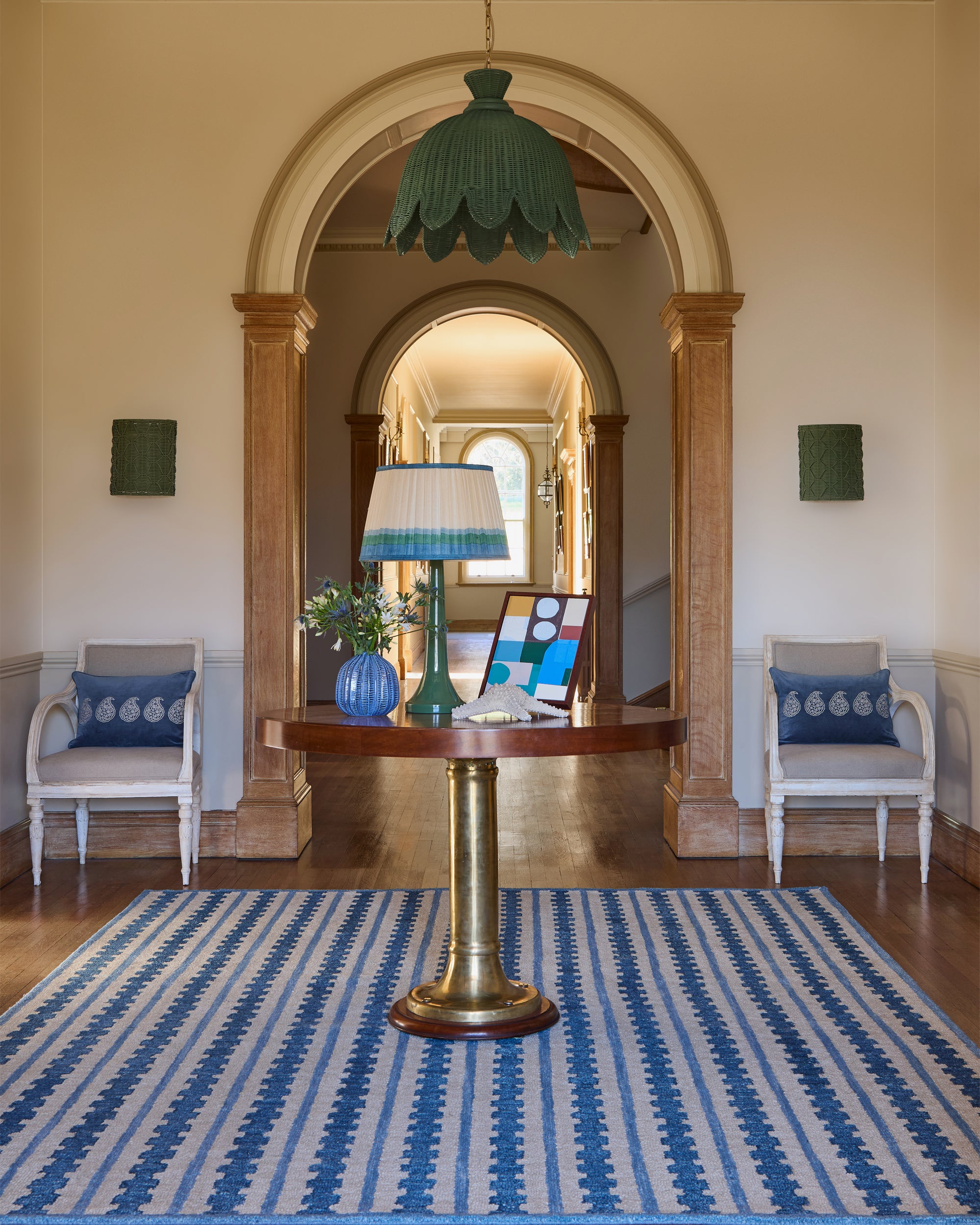Hallway with striped rug, table, chairs, and decorative elements.