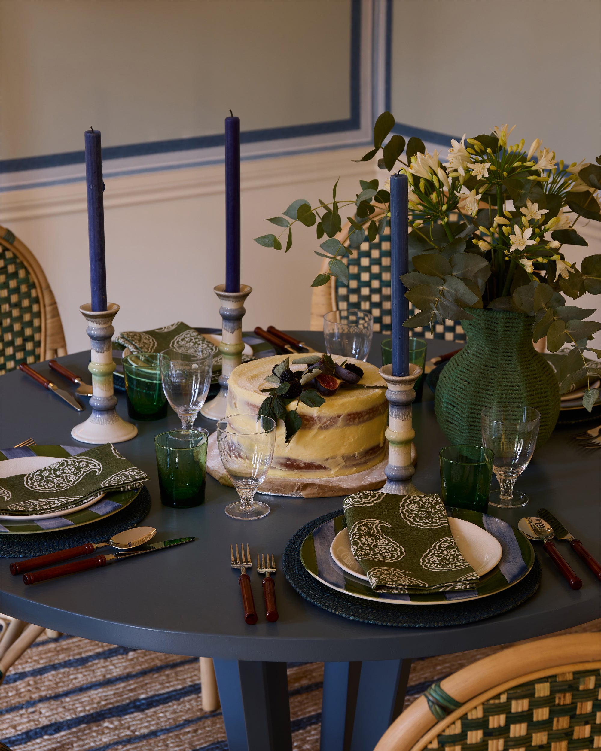 Elegant dining table setting with a cake, candles, and decorative plates.