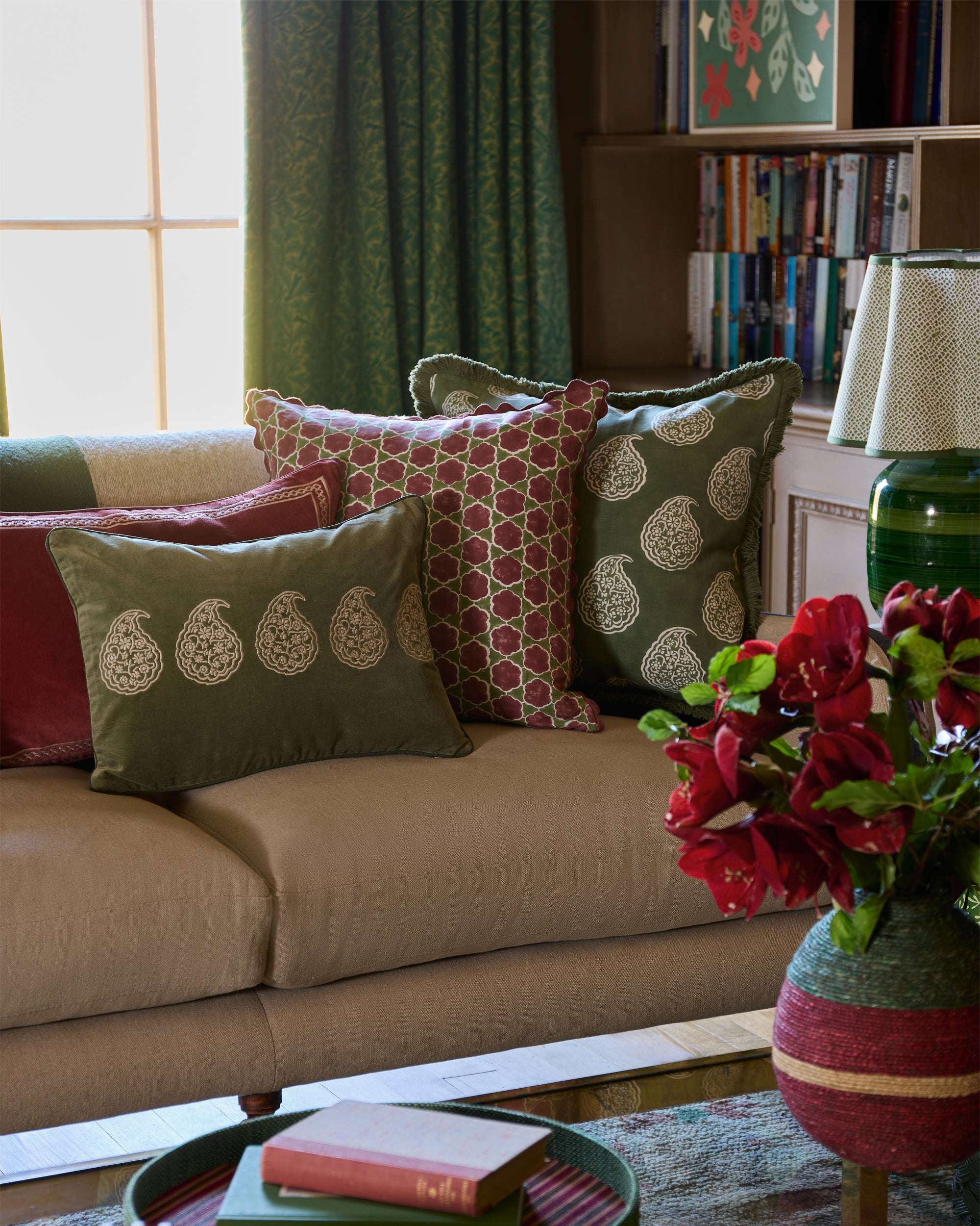 Decorative cushions on a sofa with a vase of flowers and books in the background