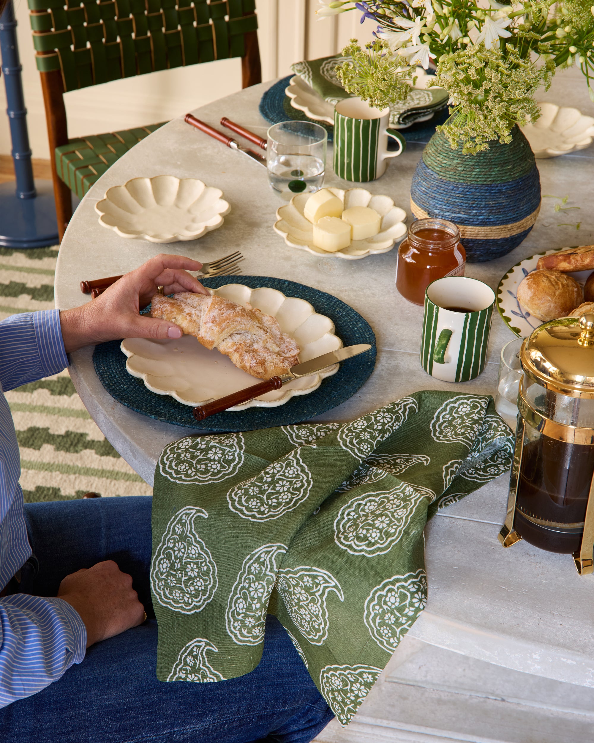 Person sitting at a dining table with a green patterned napkin, enjoying a meal.