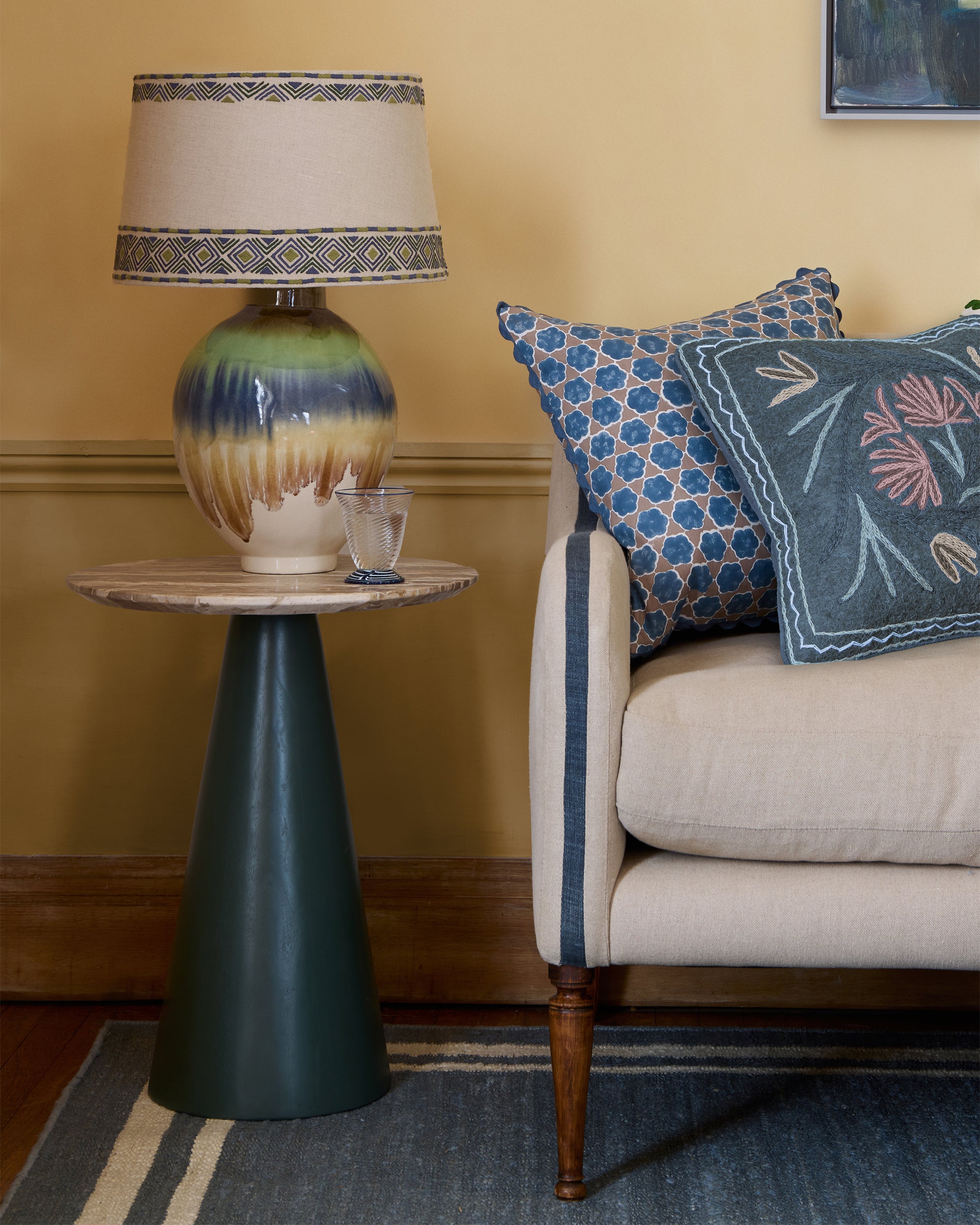 Decorative lamp on a small table next to a couch with patterned cushions in a room.