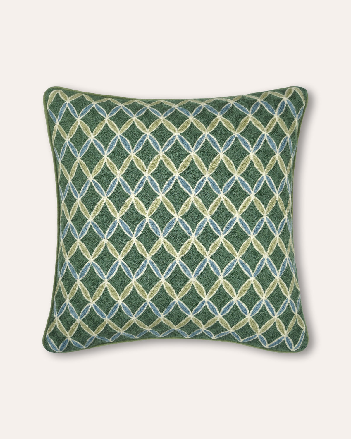 A square decorative cushion featuring an intricate geometric diamond lattice pattern in green, beige, and light blue, set against a solid off-white background.