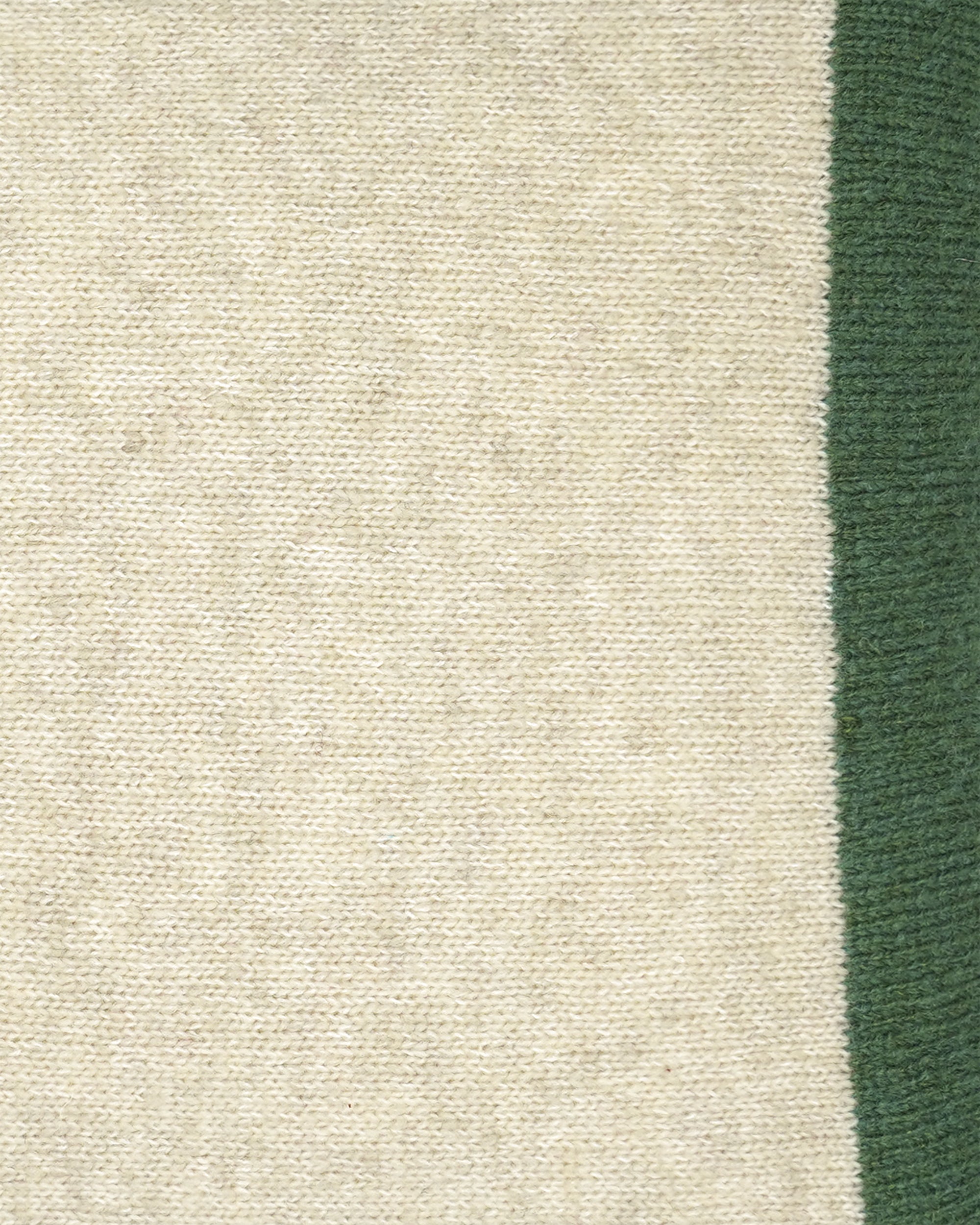 Close-up of a woven textile showing a large warm off-white/cream area and a vertical dark green stripe along the right edge.
