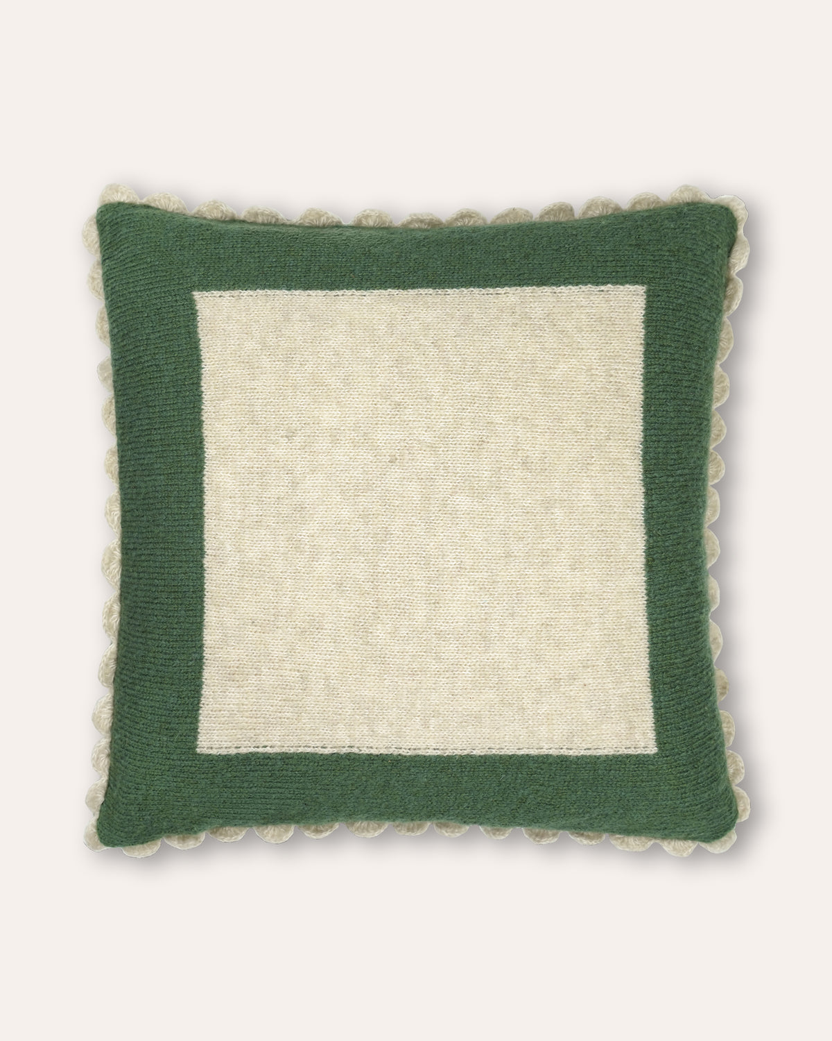 A square decorative cushion with a dark green border and a cream center panel, finished with a scalloped edge, shown against a light beige background.