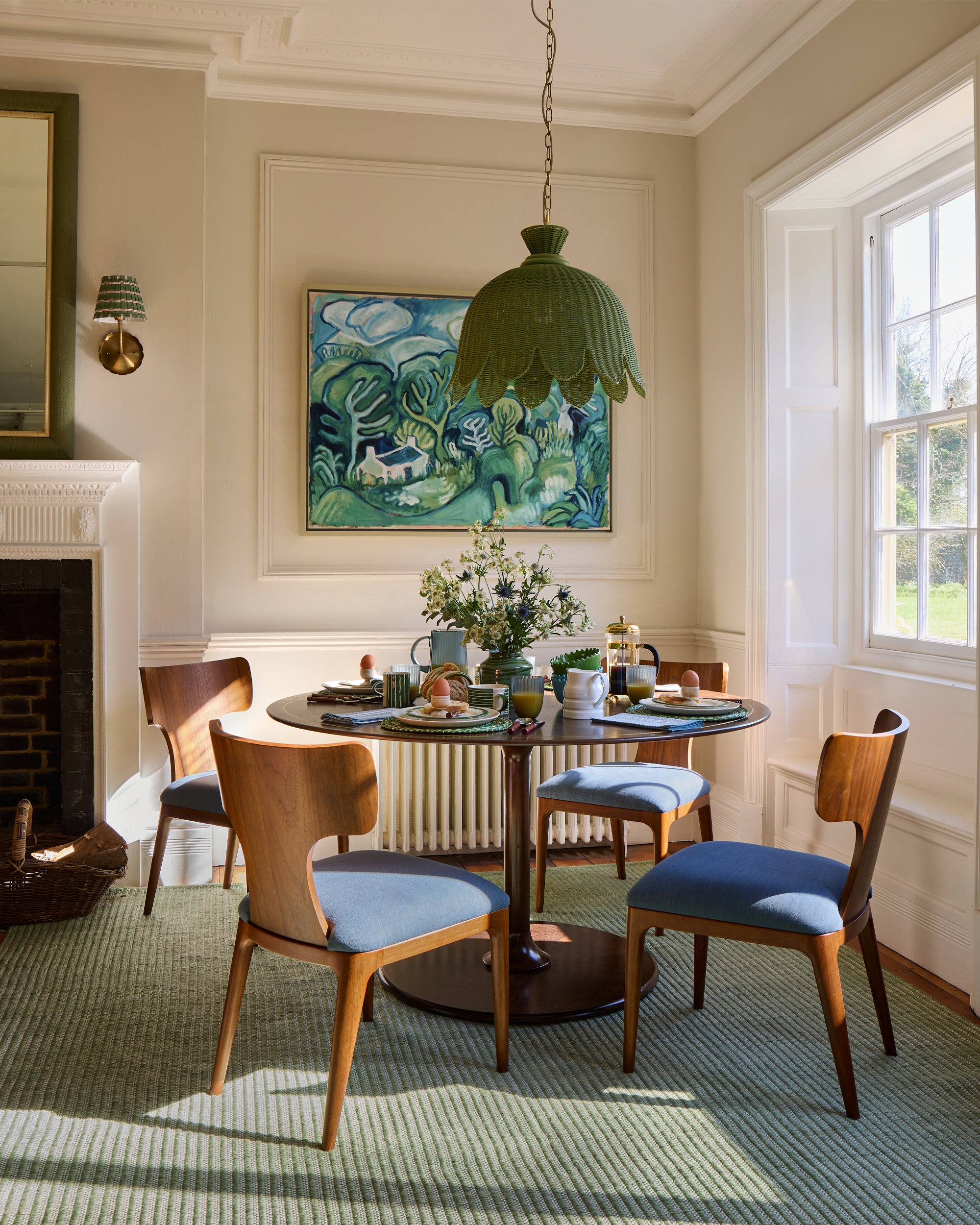 Dining room with wooden chairs, round table, and a green pendant light.
