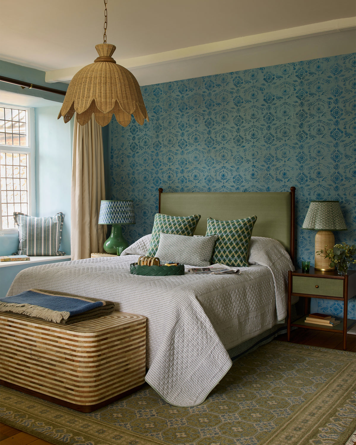 Cozy bedroom with floral wallpaper, wooden bed, and decorative cushions.
