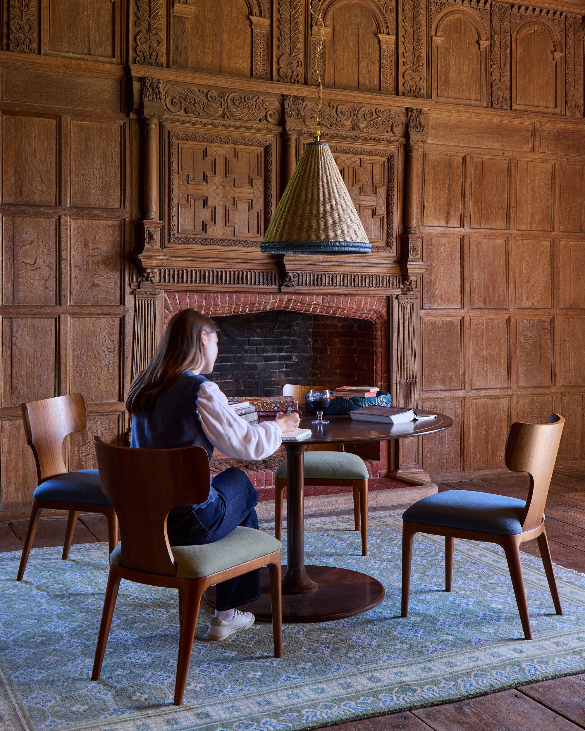 Woman sitting at a table in a room with wooden walls and chairs.