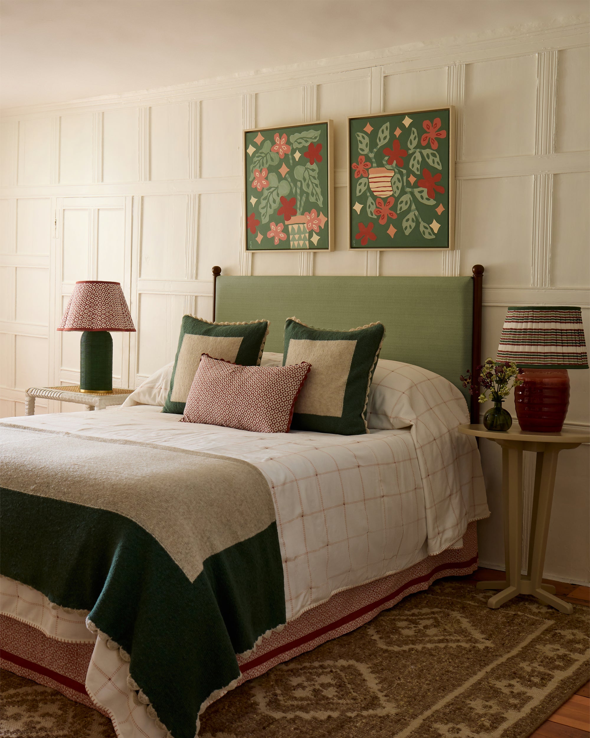Bedroom with floral wall art, green headboard, and decorative cushions.