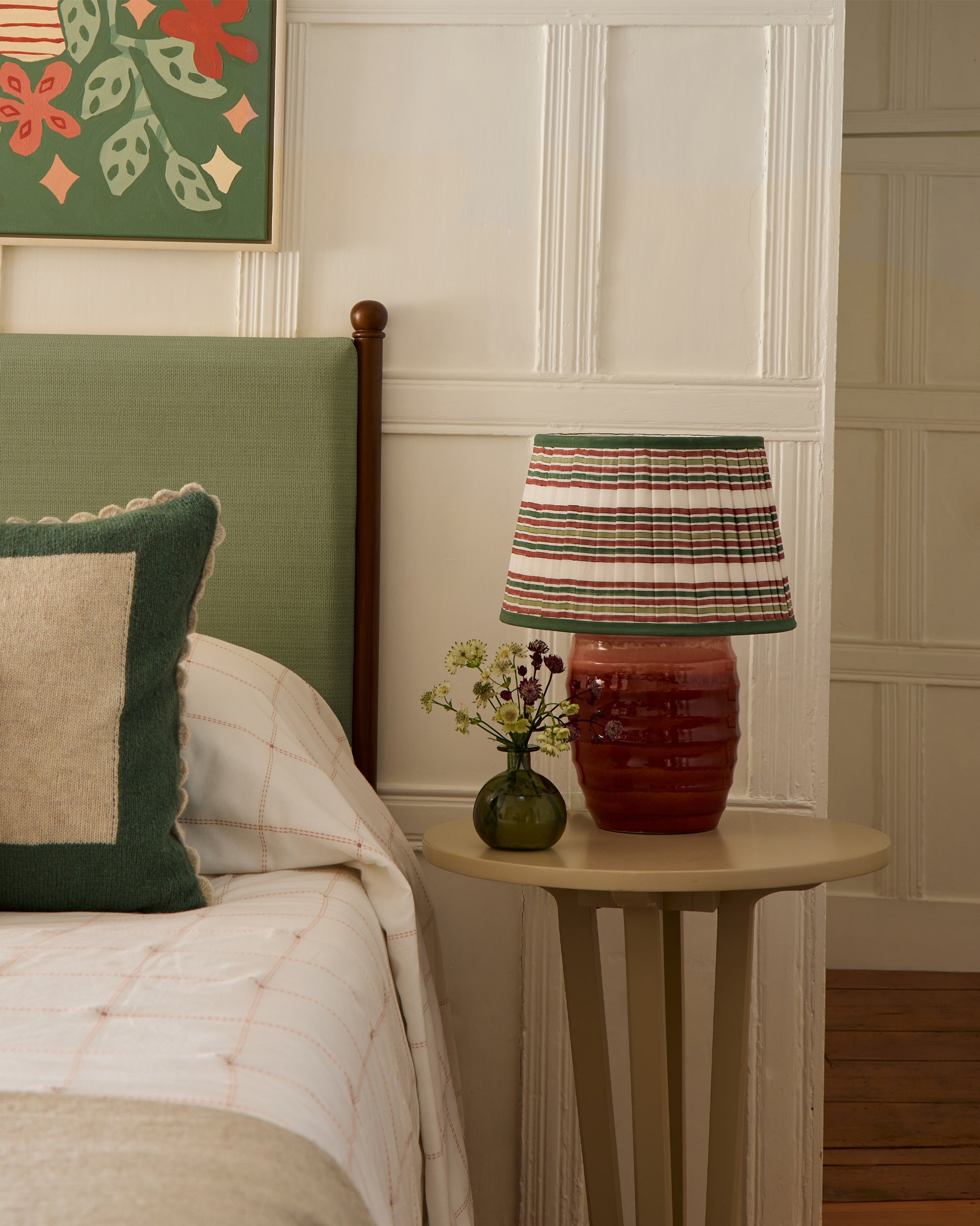 Bedroom with a bed, lamp, and decorative items on a nightstand.