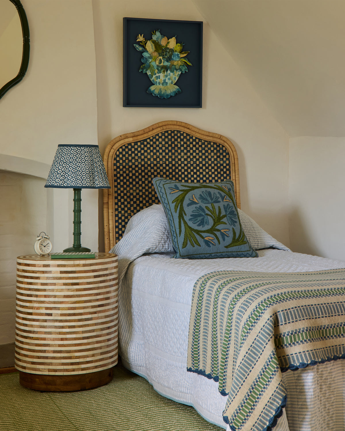 Single bedroom with rattan headboard, lamp, and decorative cushion
