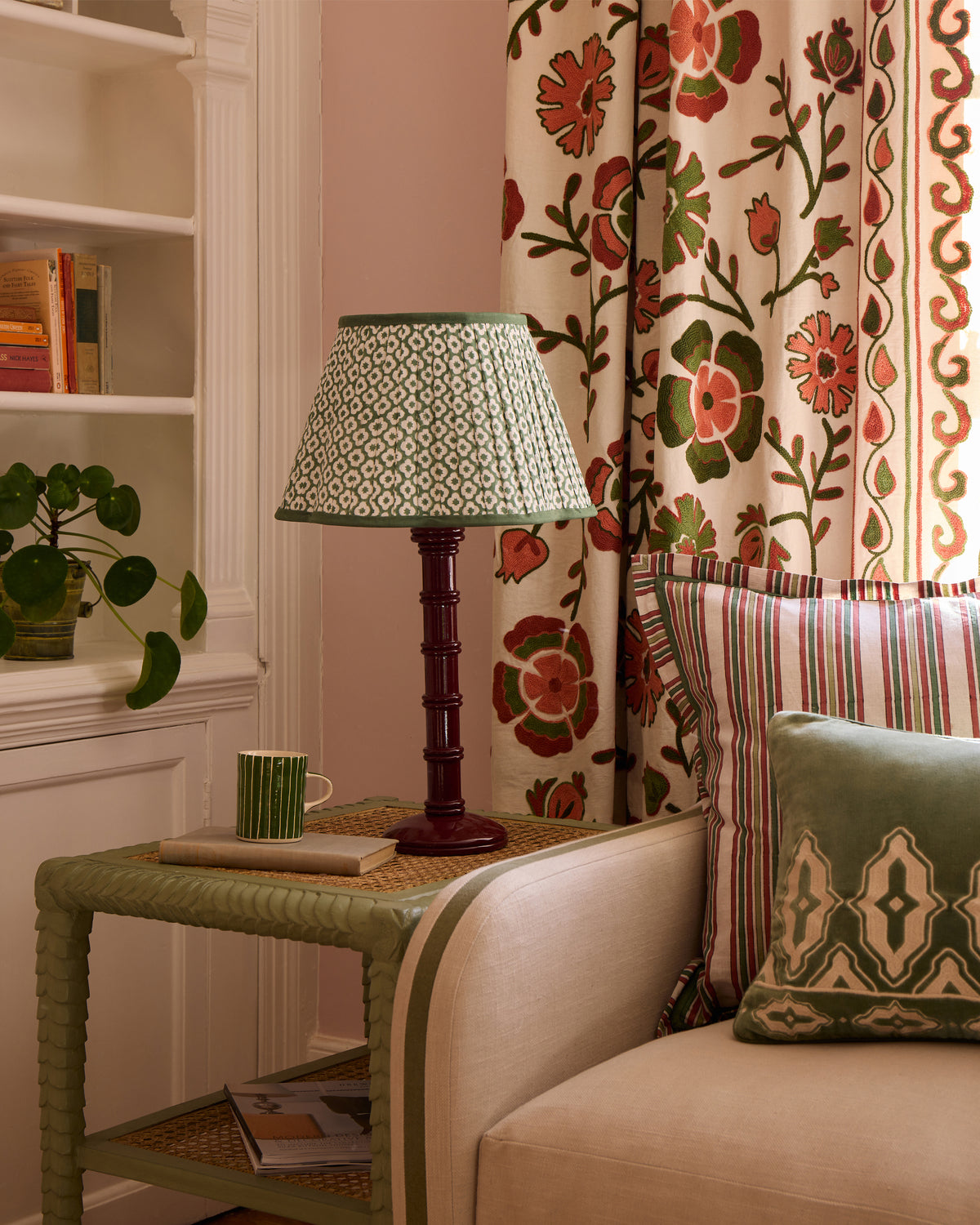 Living room corner with a lamp, mug, and decorative pillows on a sofa.