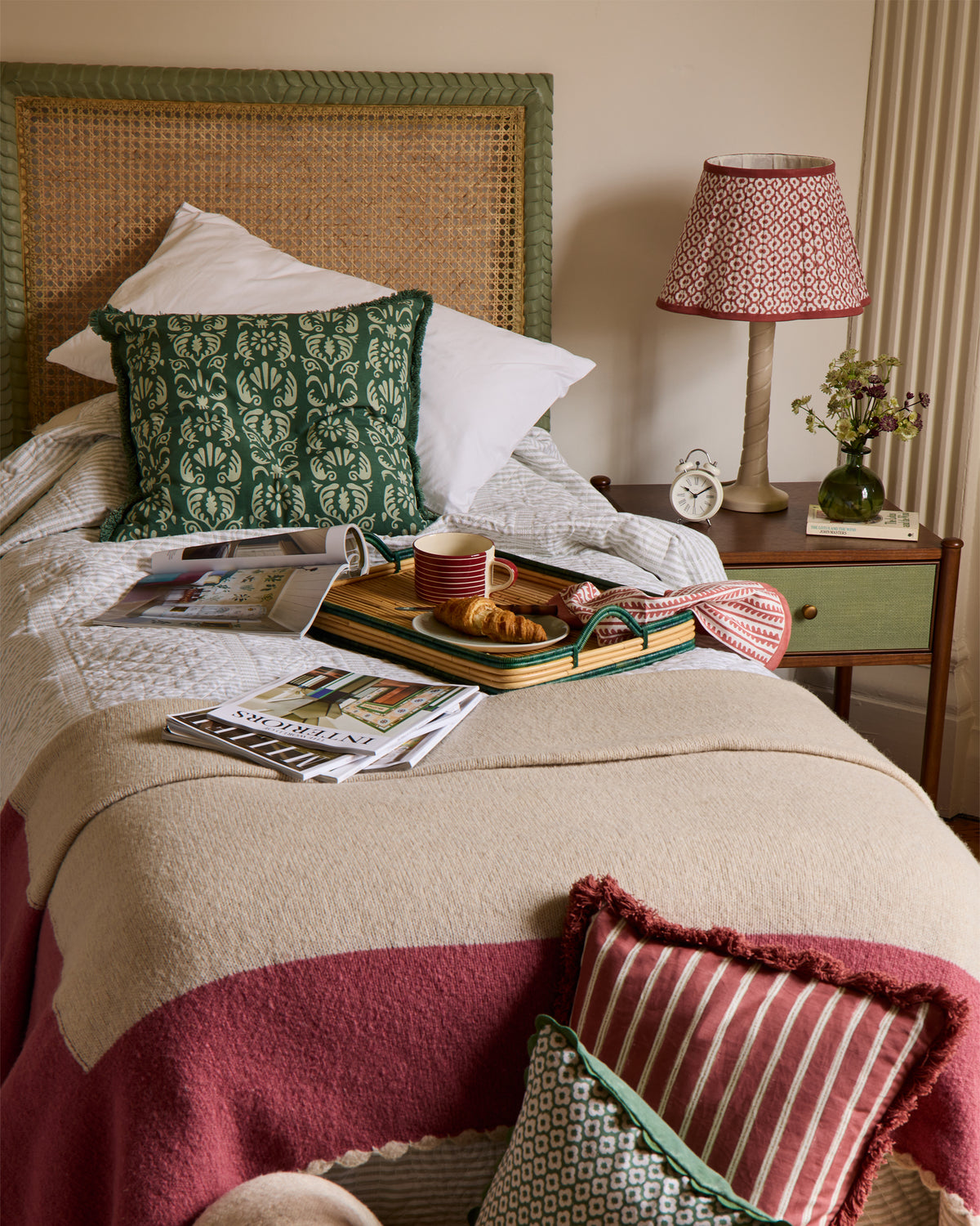 Cozy bedroom with a bed, pillows, a lamp, and a tray with food and drinks.