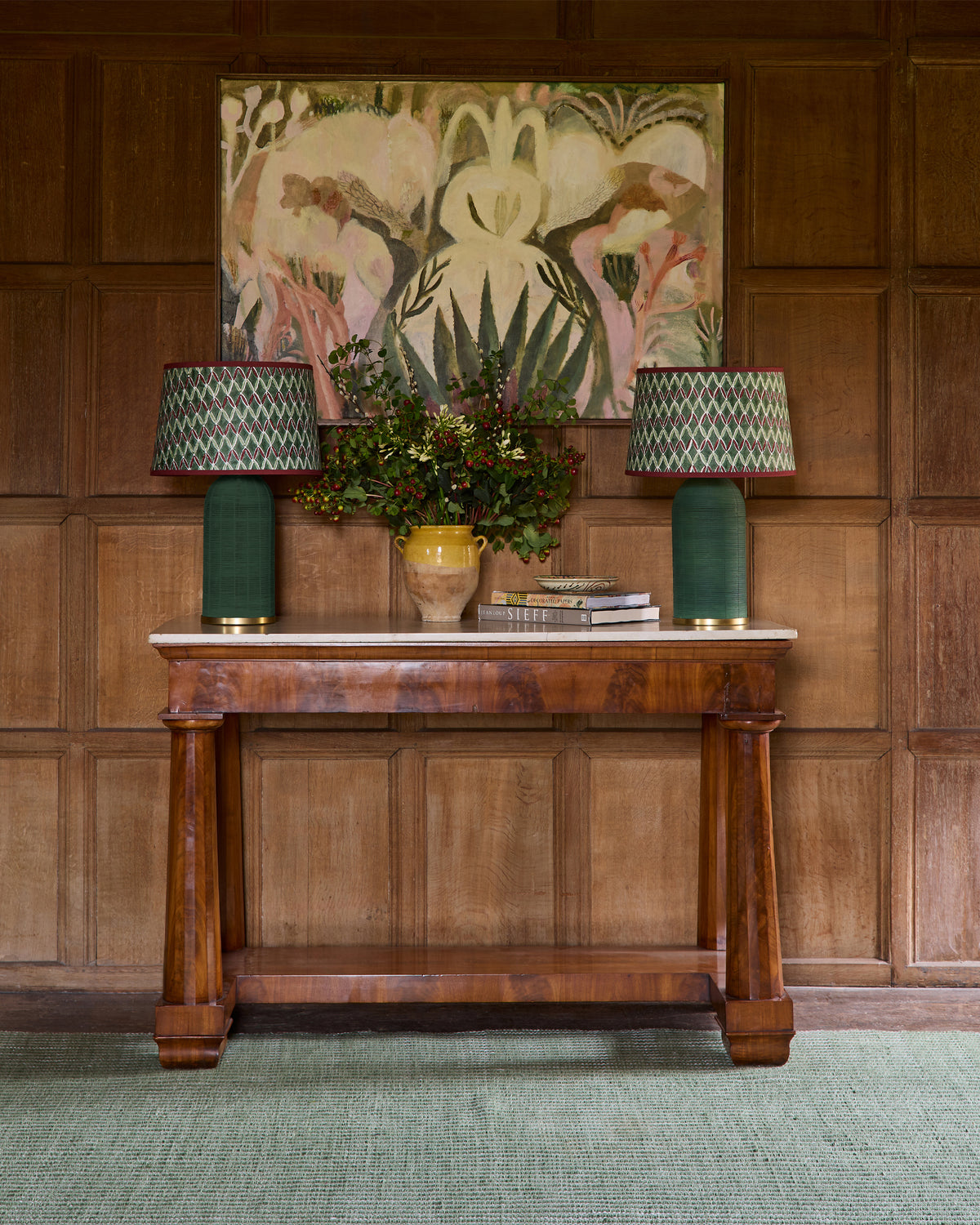 Wooden console table with lamps and decorative items against a wooden wall with a painting.