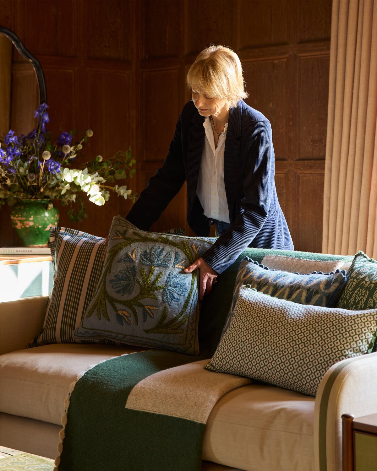 Birdie arranging decorative pillows on a sofa in a cozy living room.