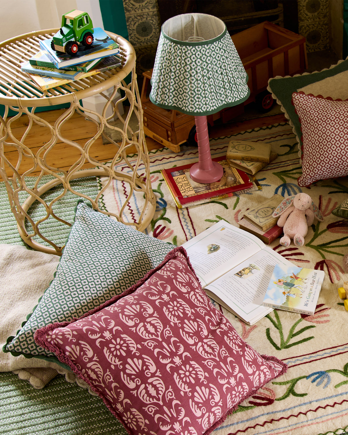 Decorative cushions on a rug with a lamp and small toys in the background