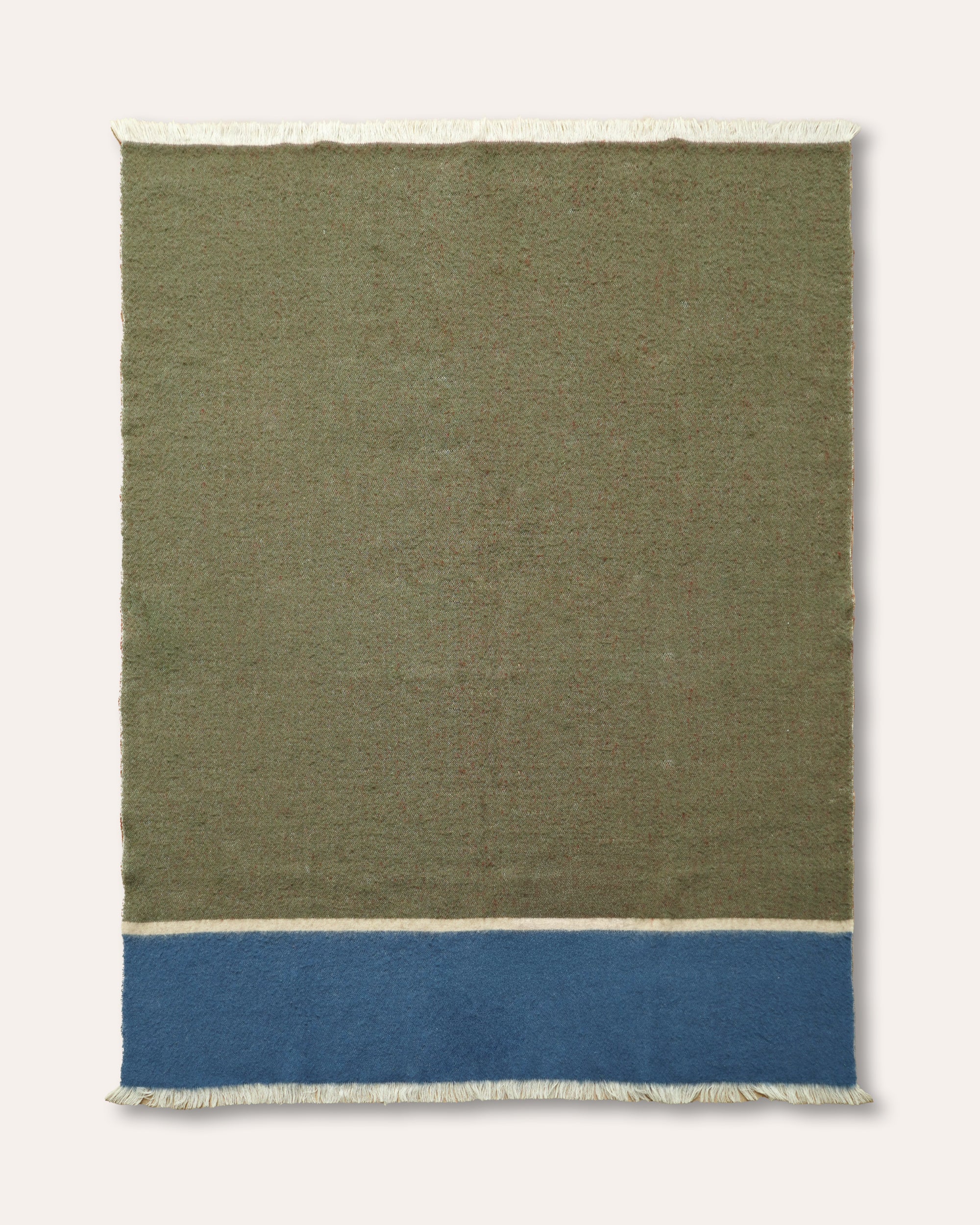 A rectangular woven throw with a large olive green field, a wide blue band near the bottom, and off-white fringe on all sides, shown against a light neutral background.
