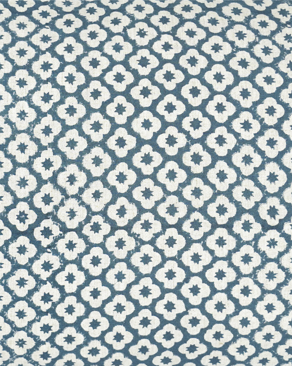A close-up of a fabric pattern featuring a repeating white quatrefoil and star motif on a muted slate blue background.