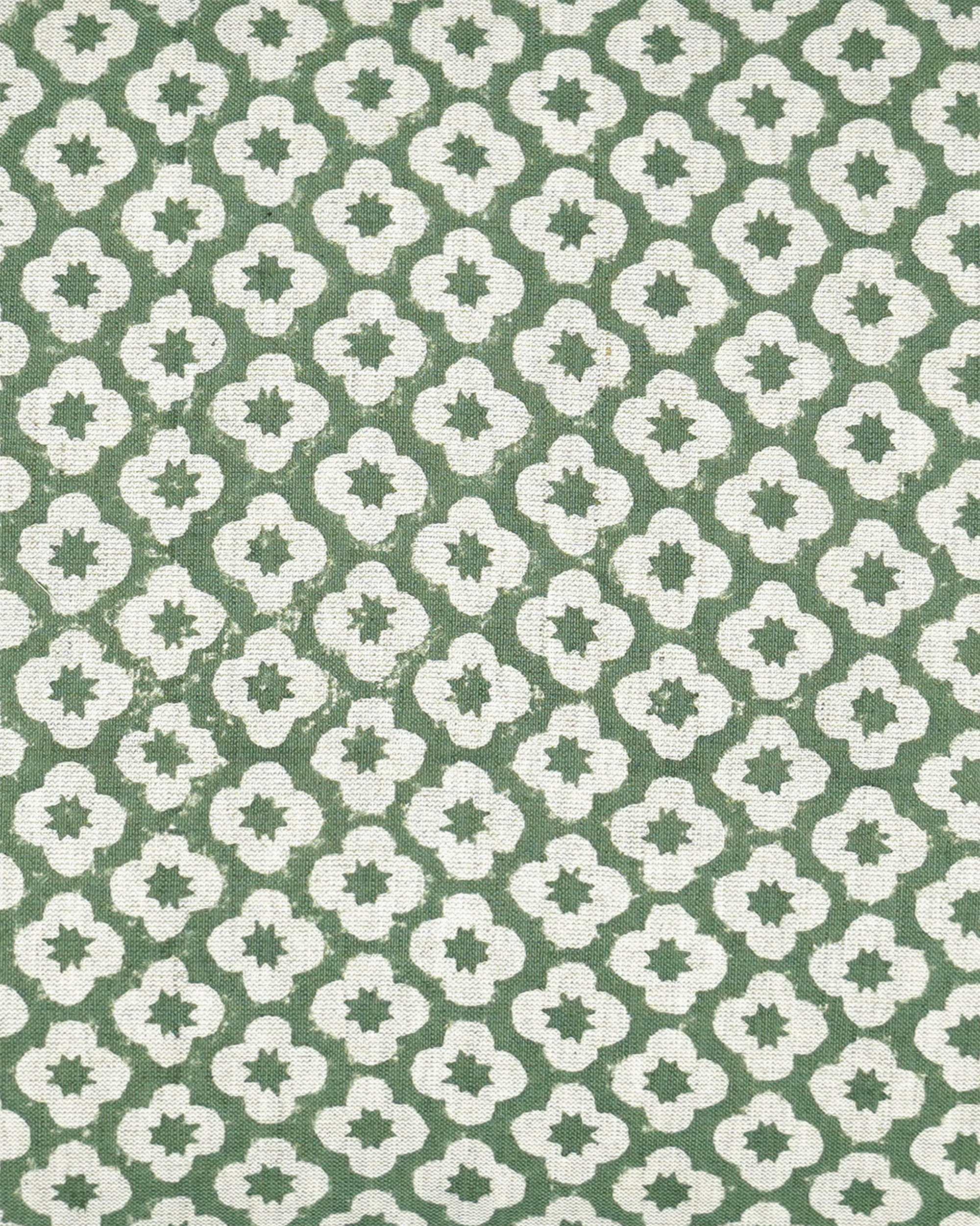 A close-up of a fabric pattern featuring a repeating white quatrefoil and star motif on a muted sage green background.